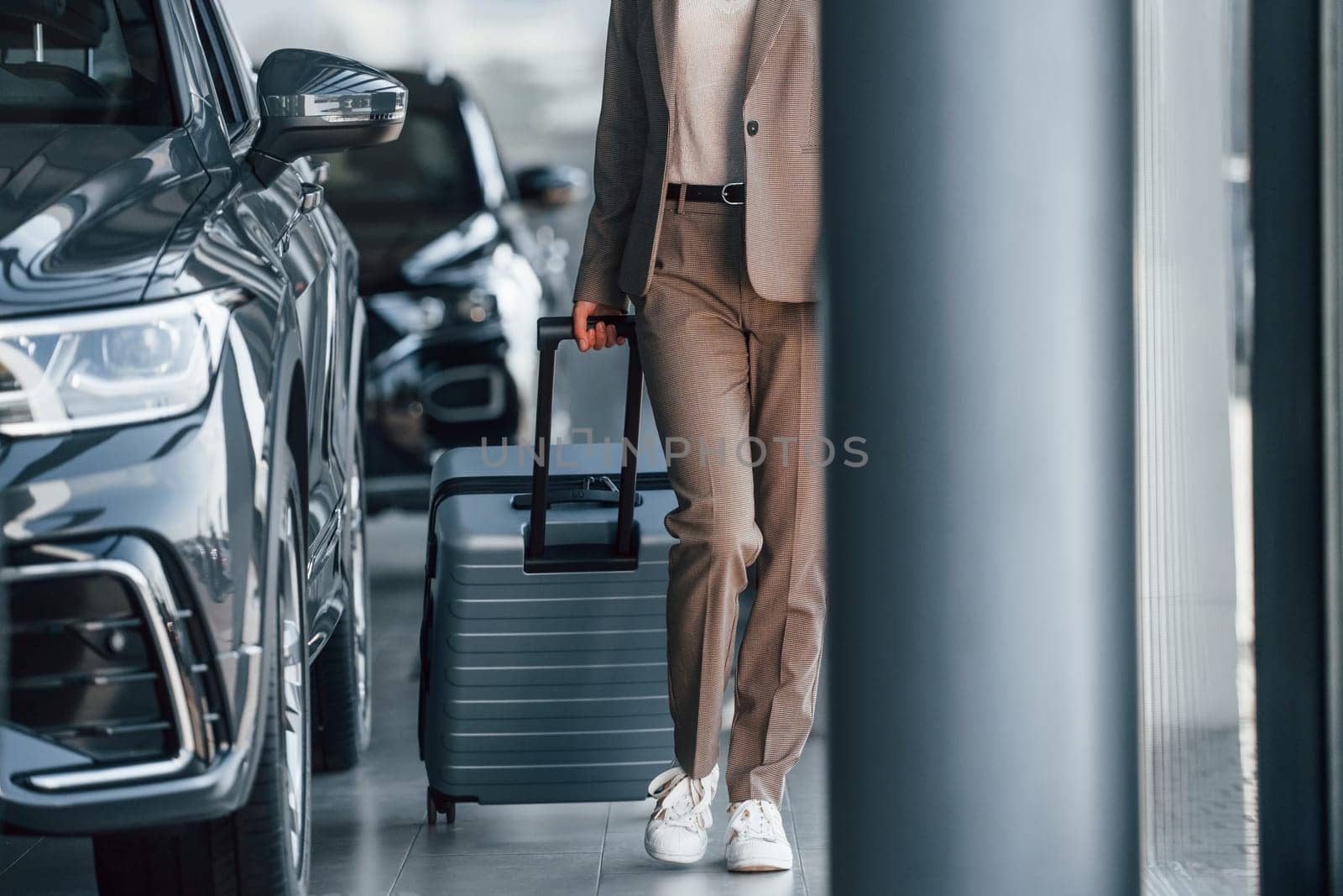 Tourist with lugagge. Woman is indoors near brand new automobile indoors.