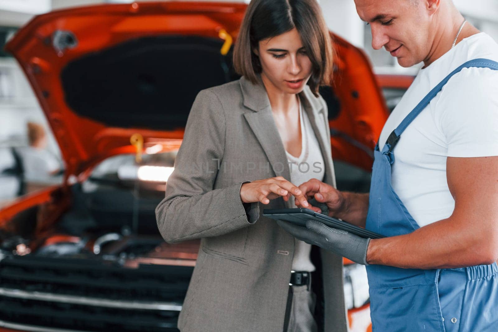 Paying for service. Man repairing woman's automobile indoors.