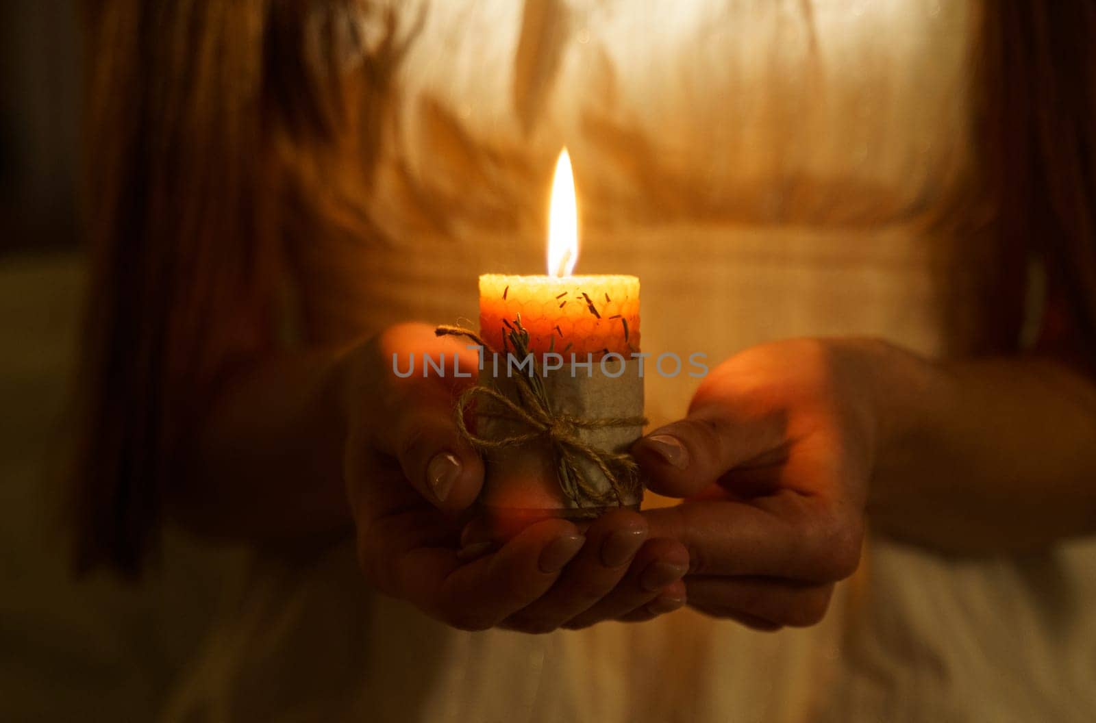 A woman holds a burning candle in her palms on a dark black background. by Sd28DimoN_1976