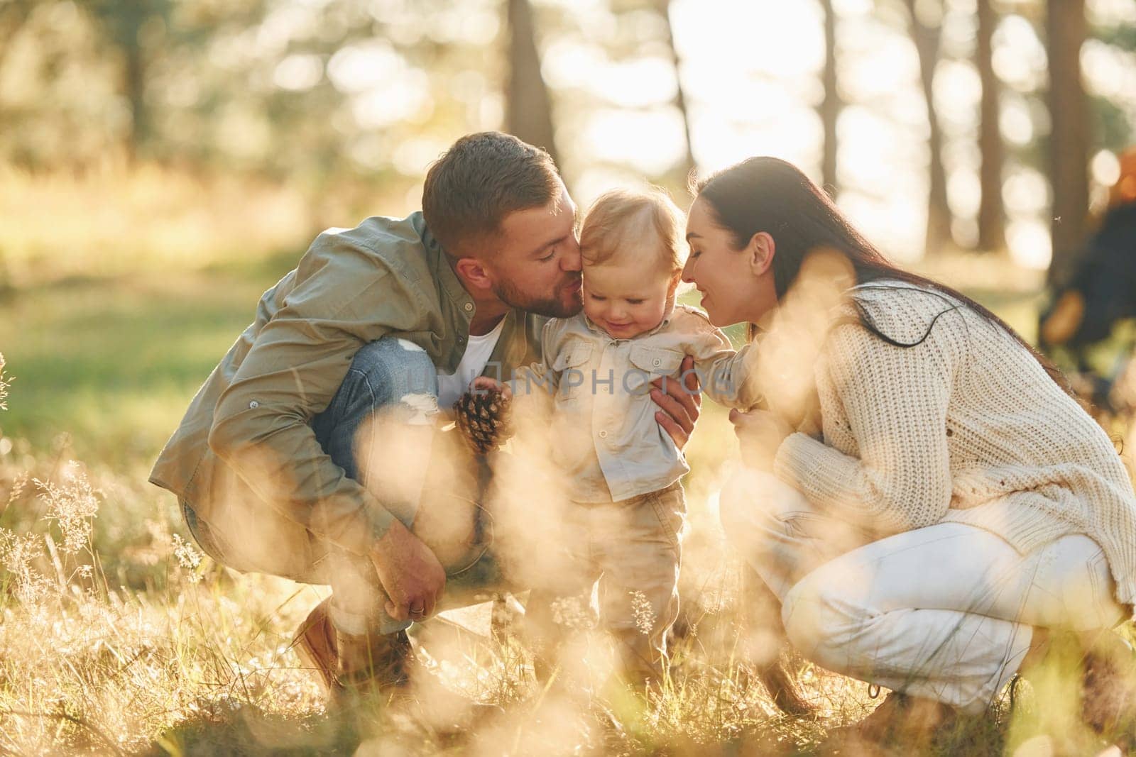 Having fun. Happy family of father, mother and little daughter is in the forest.