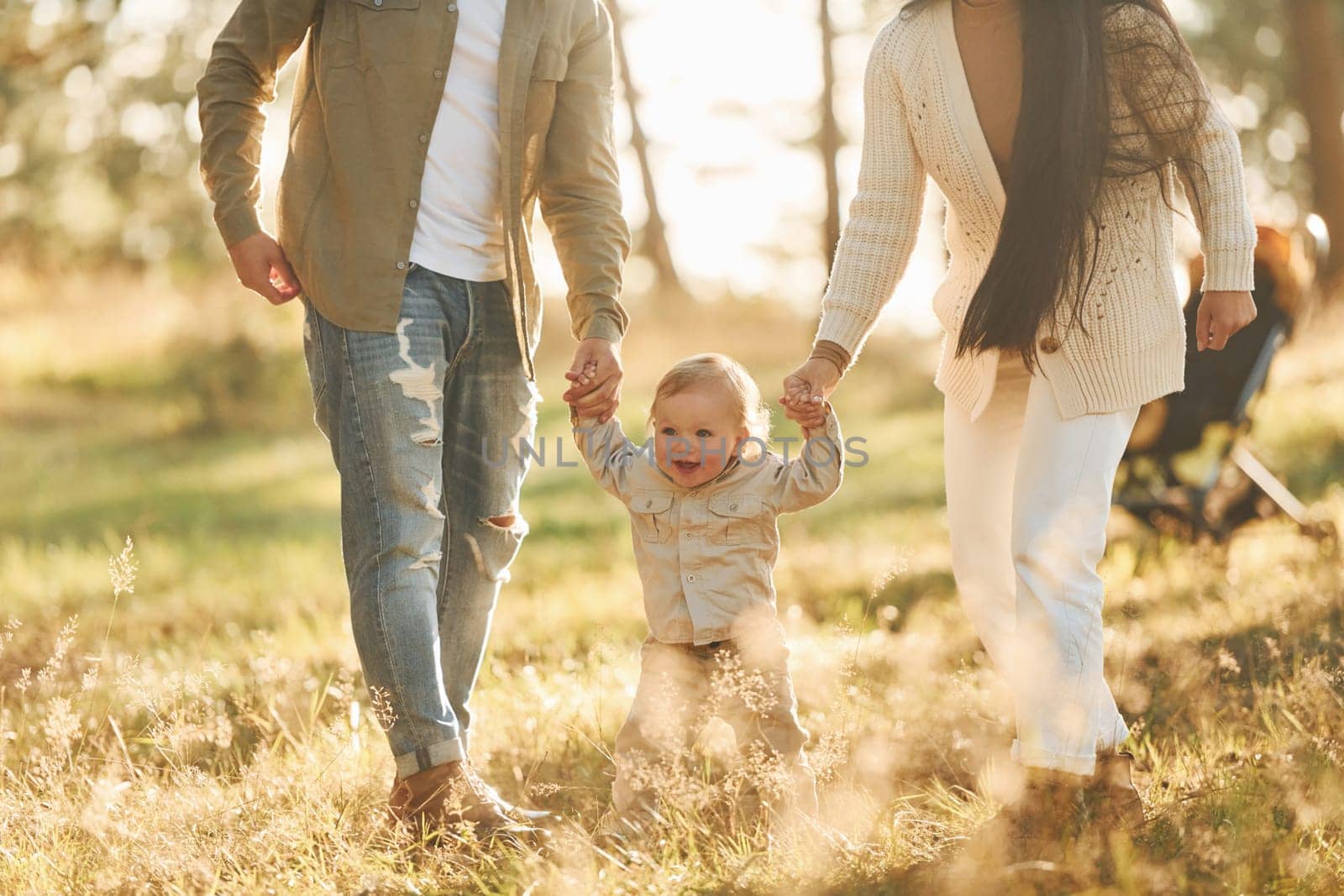 Having a walk. Happy family of father, mother and little daughter is in the forest.