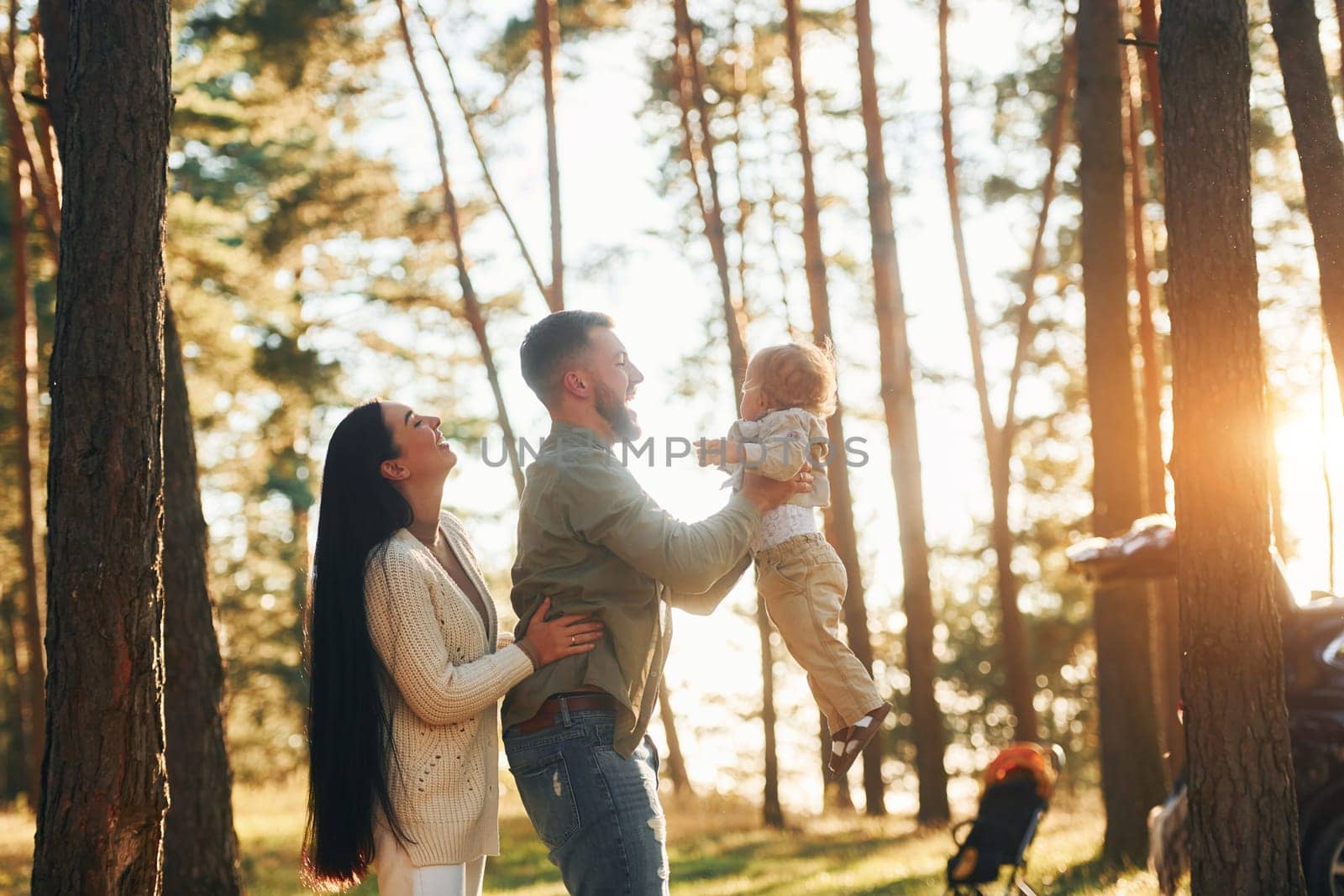 Having a walk. Happy family of father, mother and little daughter is in the forest.