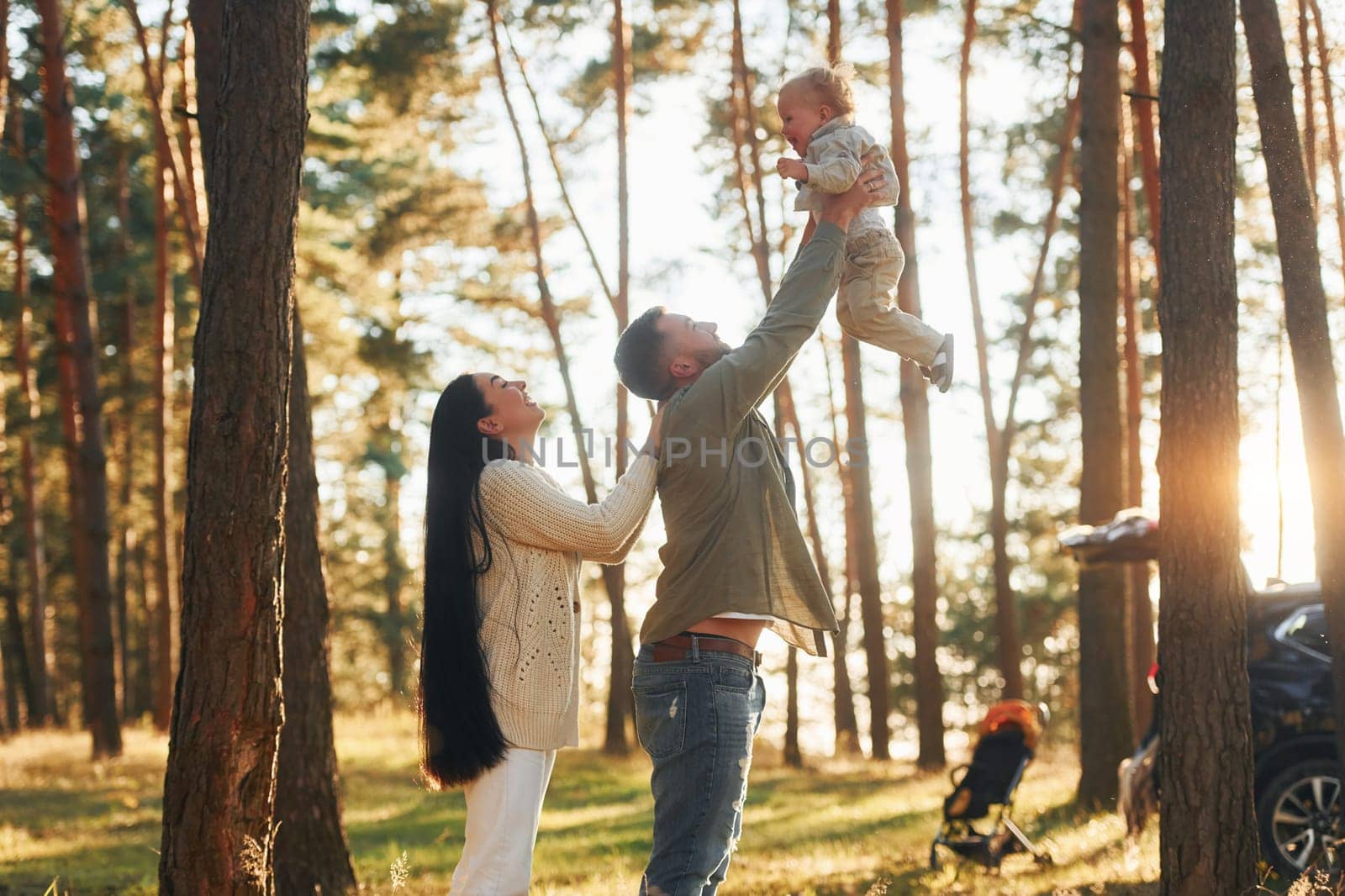 Summertime happiness. Family of father, mother and little daughter is in the forest.