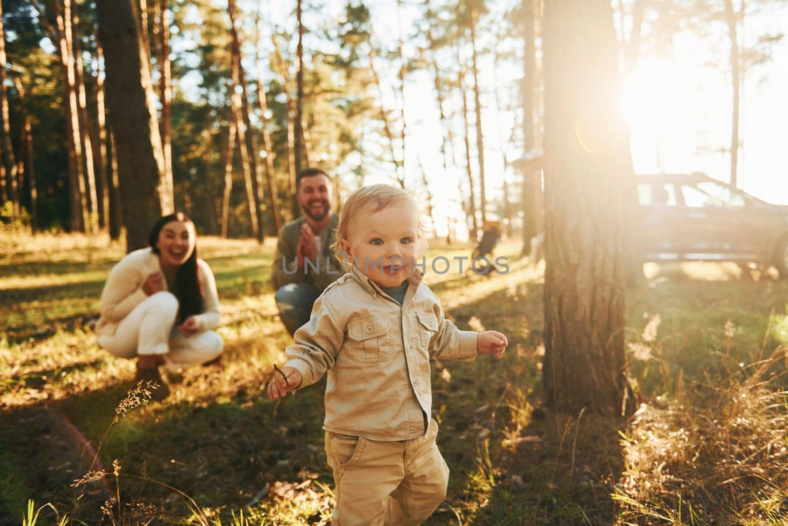 Summertime happiness. Family of father, mother and little daughter is in the forest.