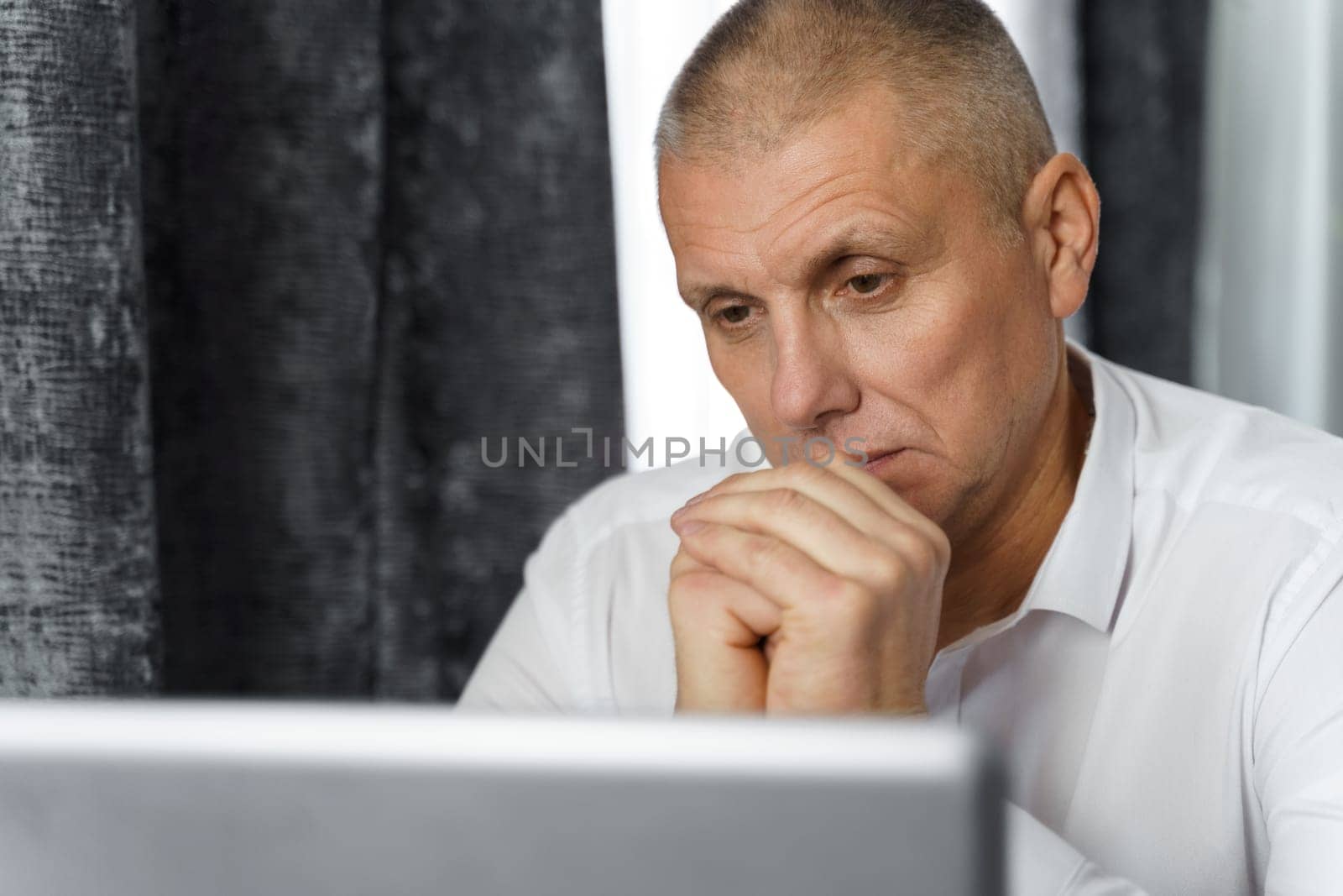 Pensive businessman, manager creates new business ideas while sitting at a table with a laptop. Close-up by Sd28DimoN_1976