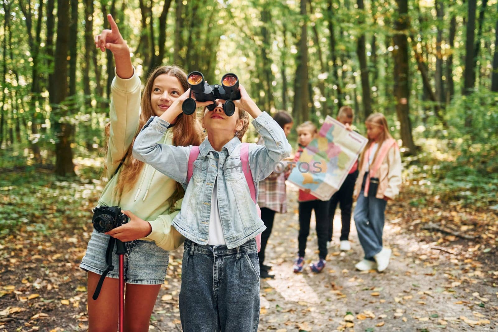 Conception of tourism. Kids in green forest at summer daytime together.