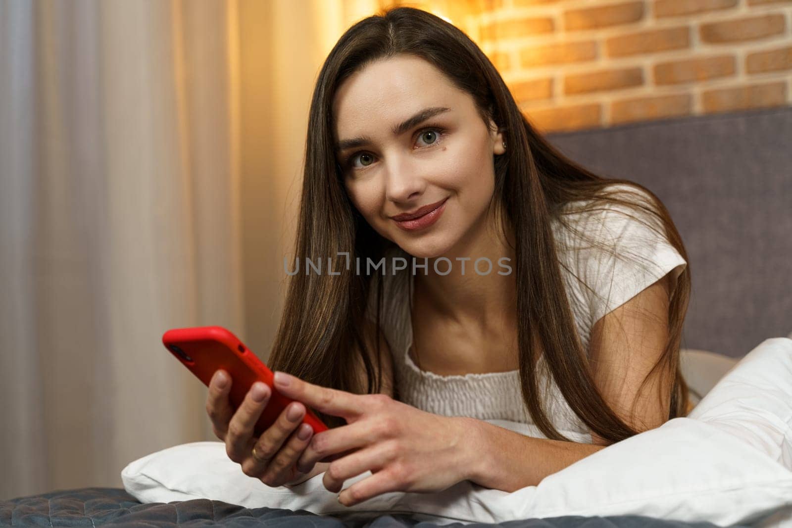 Portrait of a young woman who lies with a smartphone in her hands in the evening on the bed. by Sd28DimoN_1976
