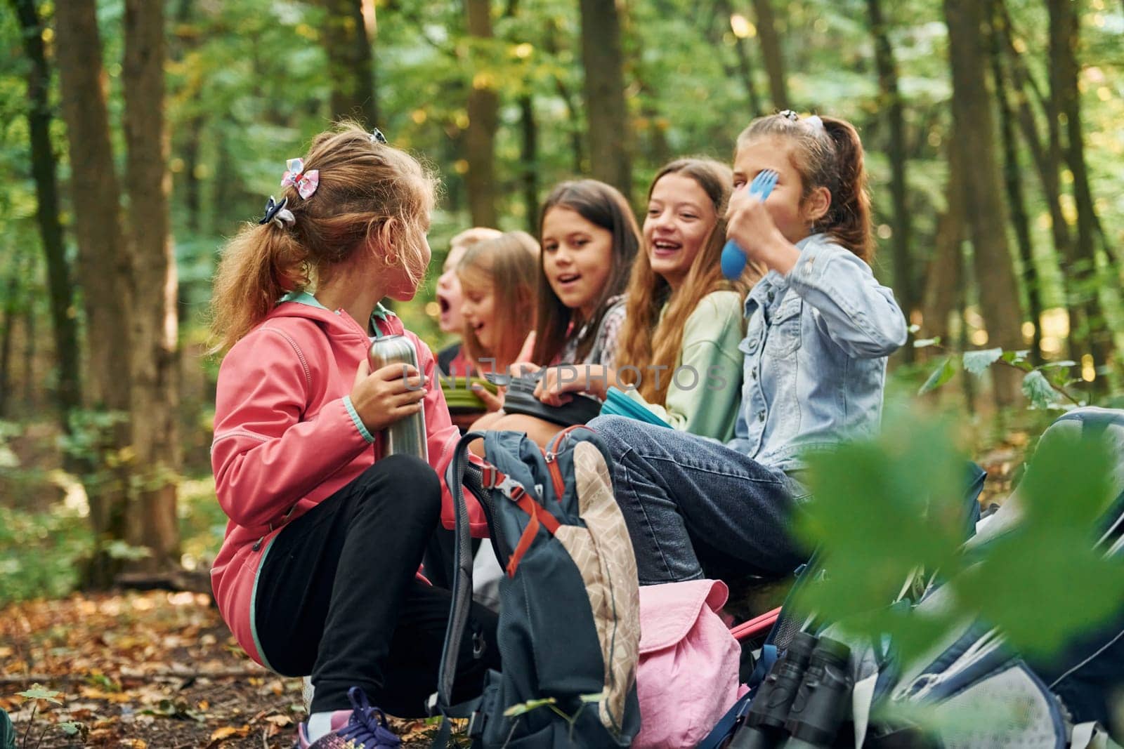 Sitting and having a rest. Kids in green forest at summer daytime together.