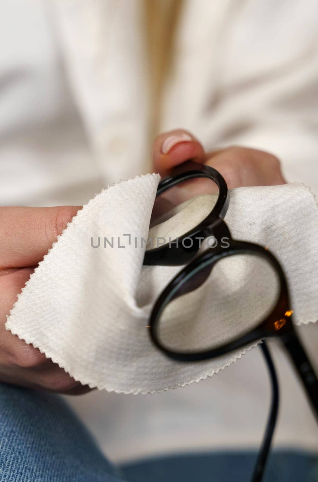 Close-up of women's hands cleaning glasses with a special cloth. Vertical frame.