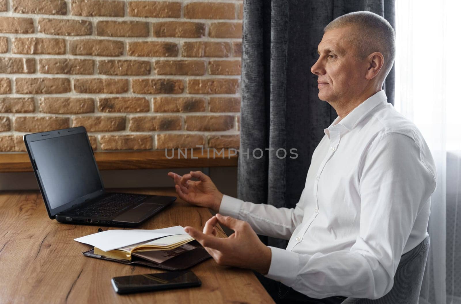 A businessman meditates while working on a laptop, sitting with his eyes closed at his workplace in a home interior. by Sd28DimoN_1976