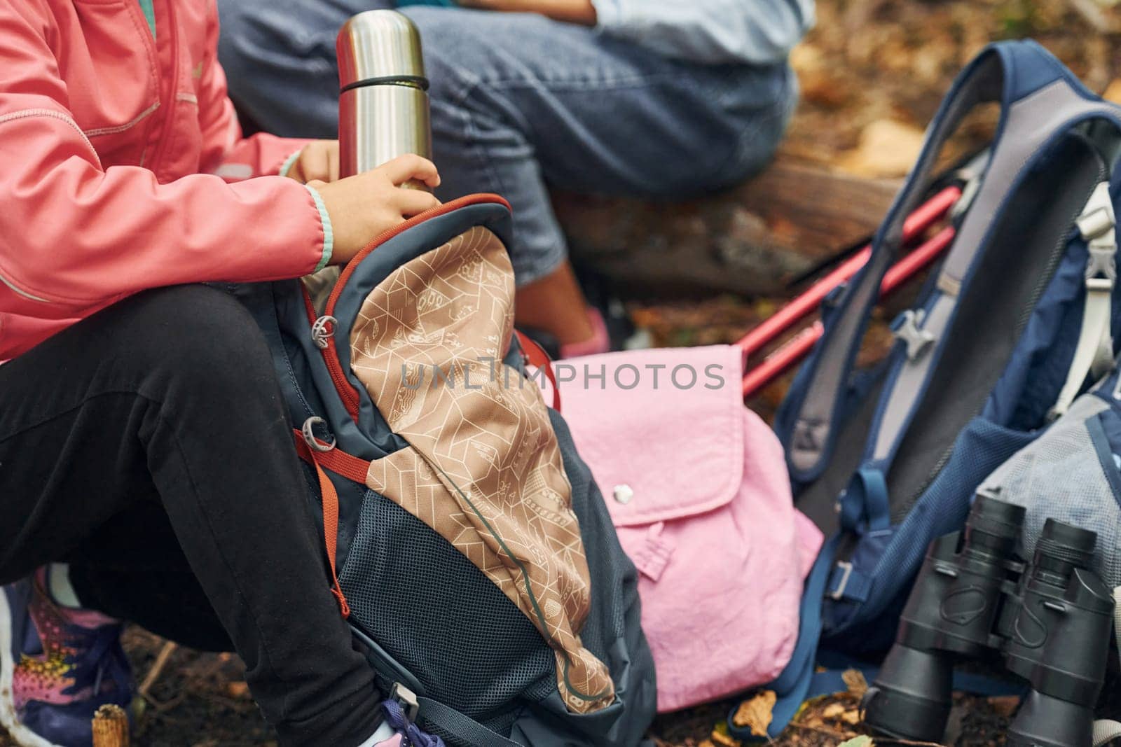 Two people sitting and resting. Kids in green forest at summer daytime together.