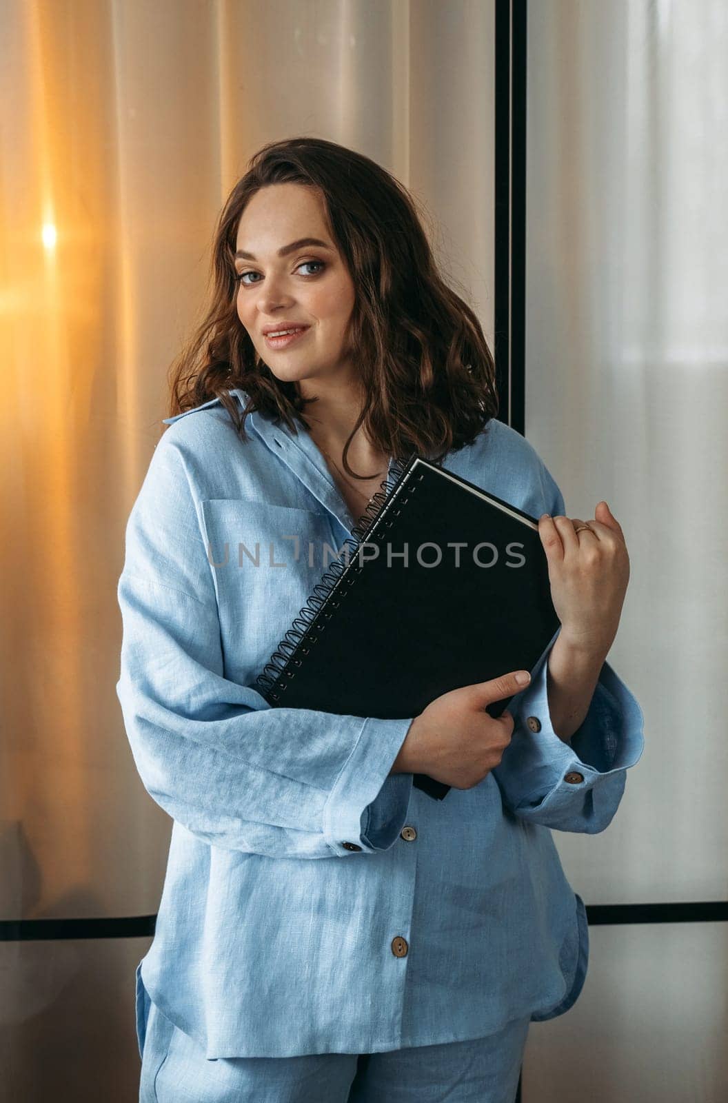 A portrait of a young woman in a light blue suit is standing in a room with a tablet and a notebook in her hands. by Sd28DimoN_1976