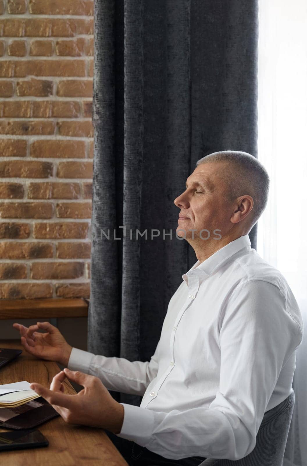 A businessman meditates while working on a laptop, sitting with his eyes closed at his workplace in a home interior. by Sd28DimoN_1976