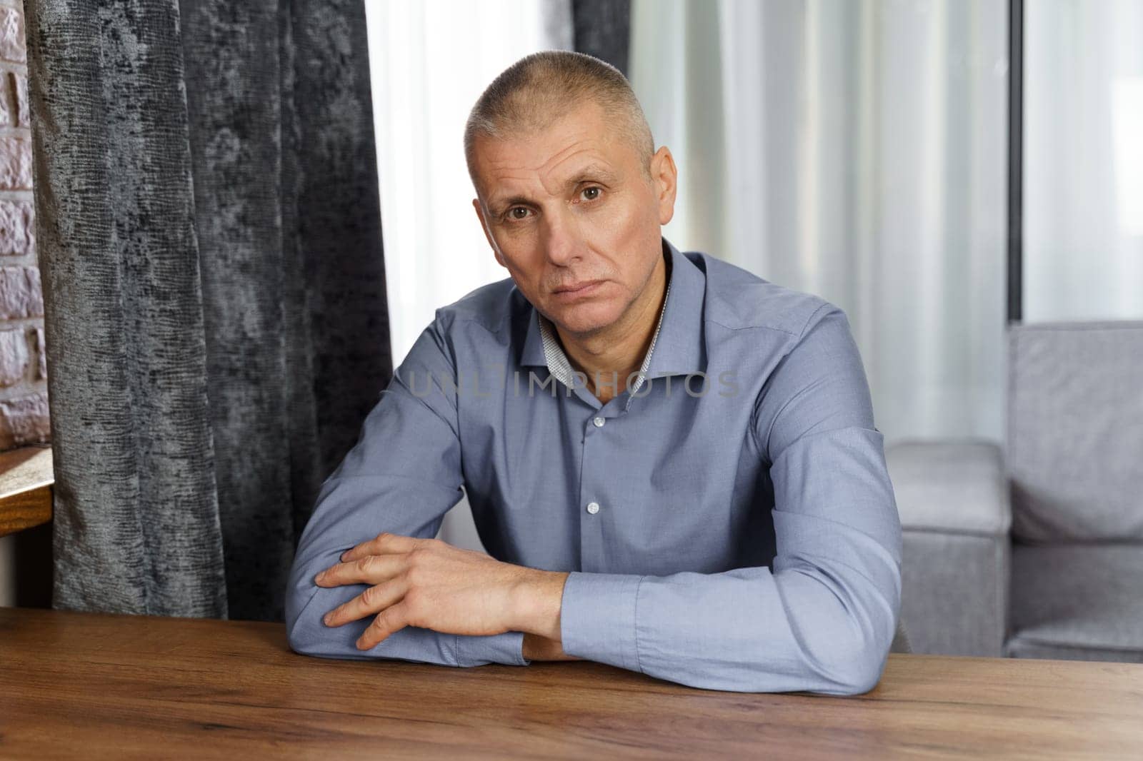 A portrait of a serious man holding his hand on his face and looking into the cell. Close-up.