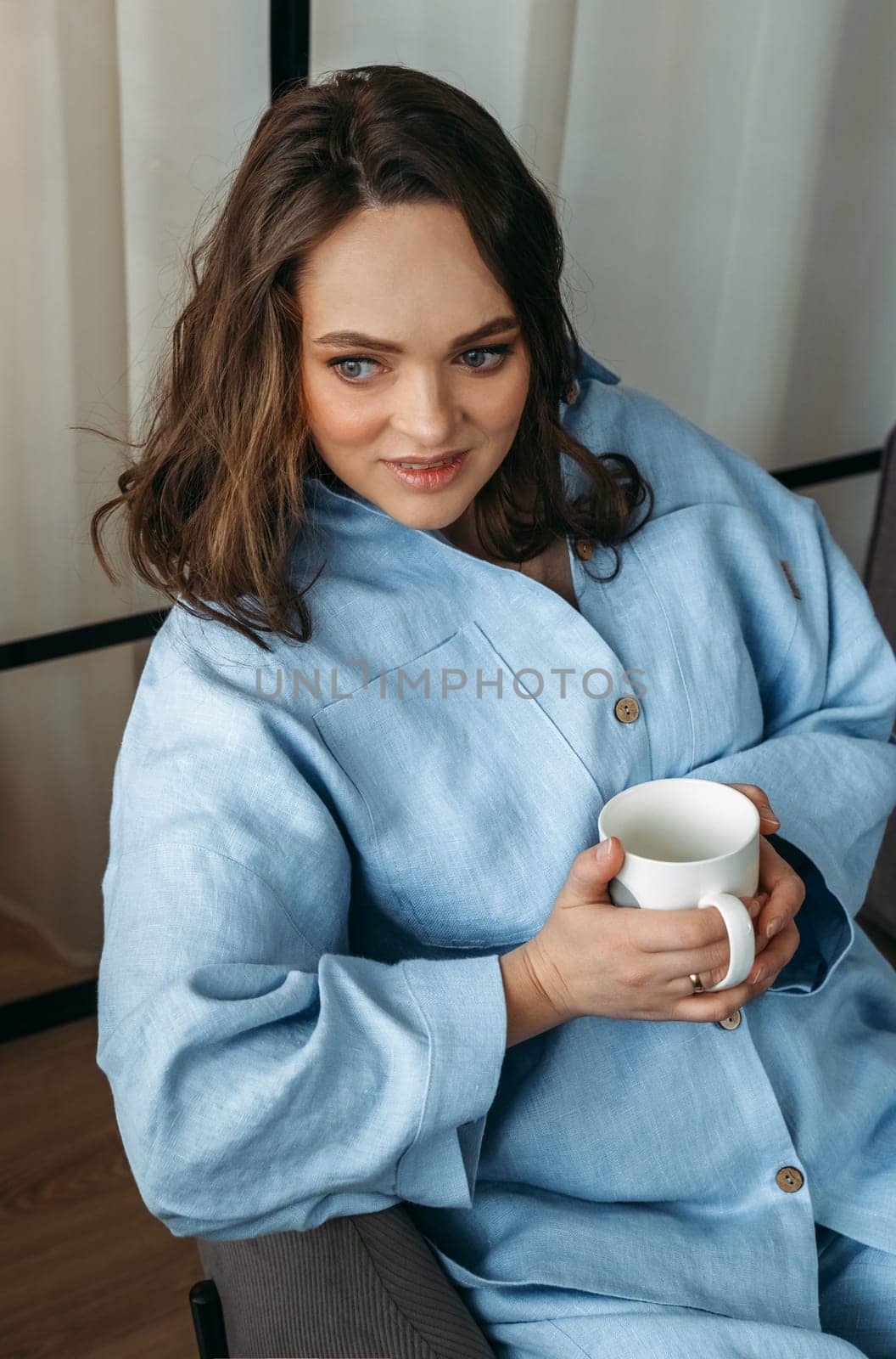 Portrait of a young woman in a light blue suit, who is sitting on a chair with a white cup in her hands by Sd28DimoN_1976