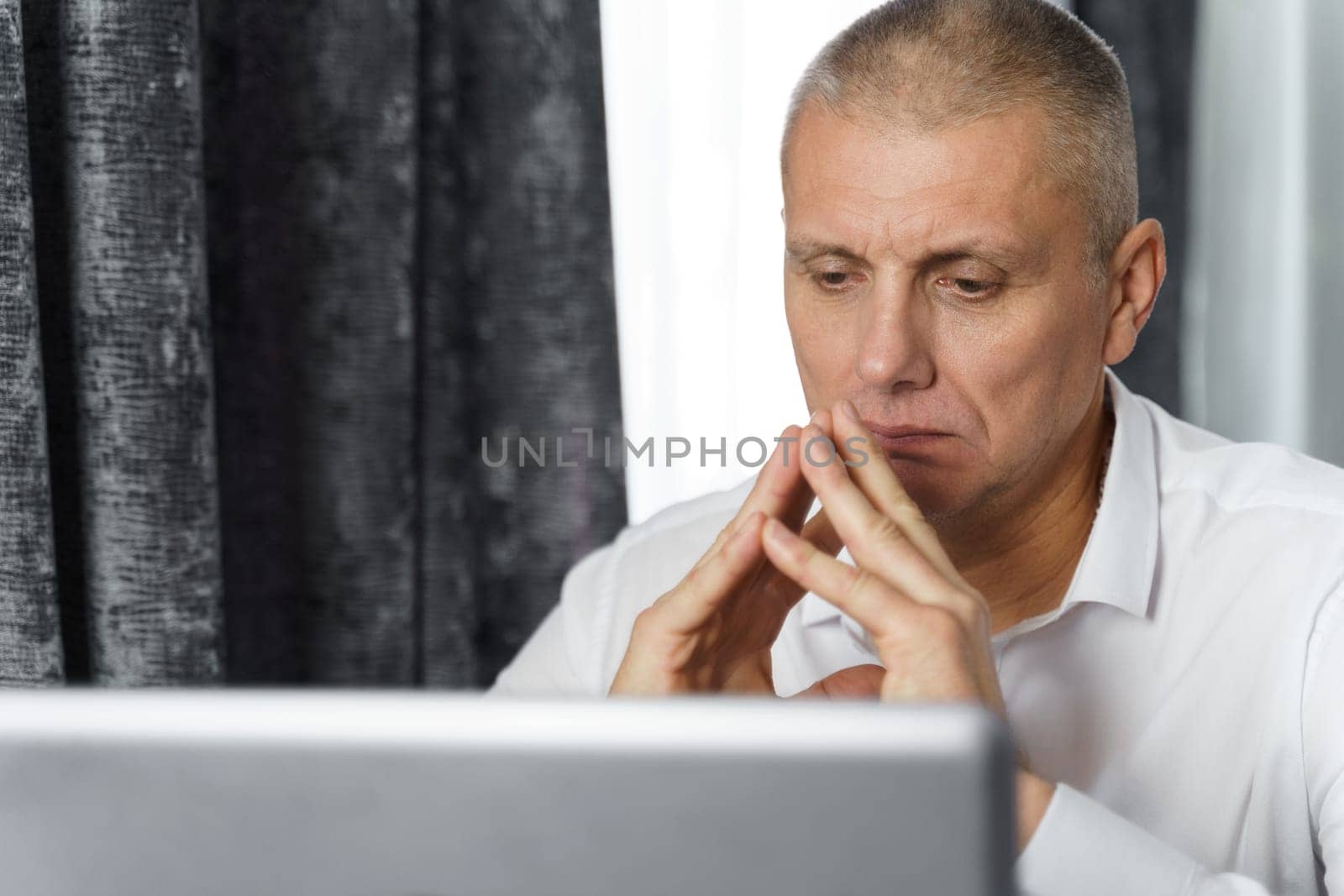 Pensive businessman, manager creates new business ideas while sitting at a table with a laptop. by Sd28DimoN_1976
