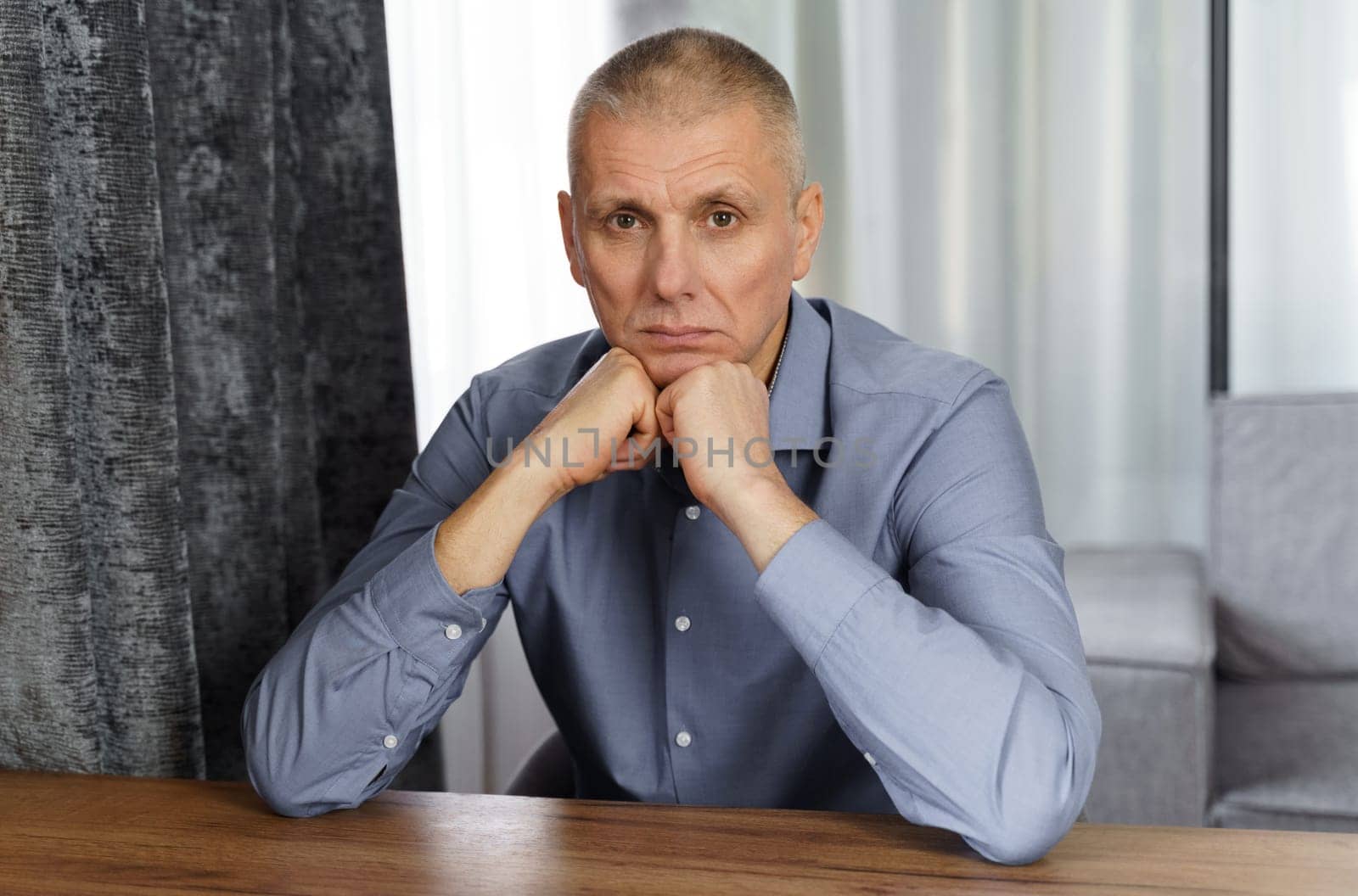 A portrait of a serious man holding his hand on his face and looking into the cell. Close-up.