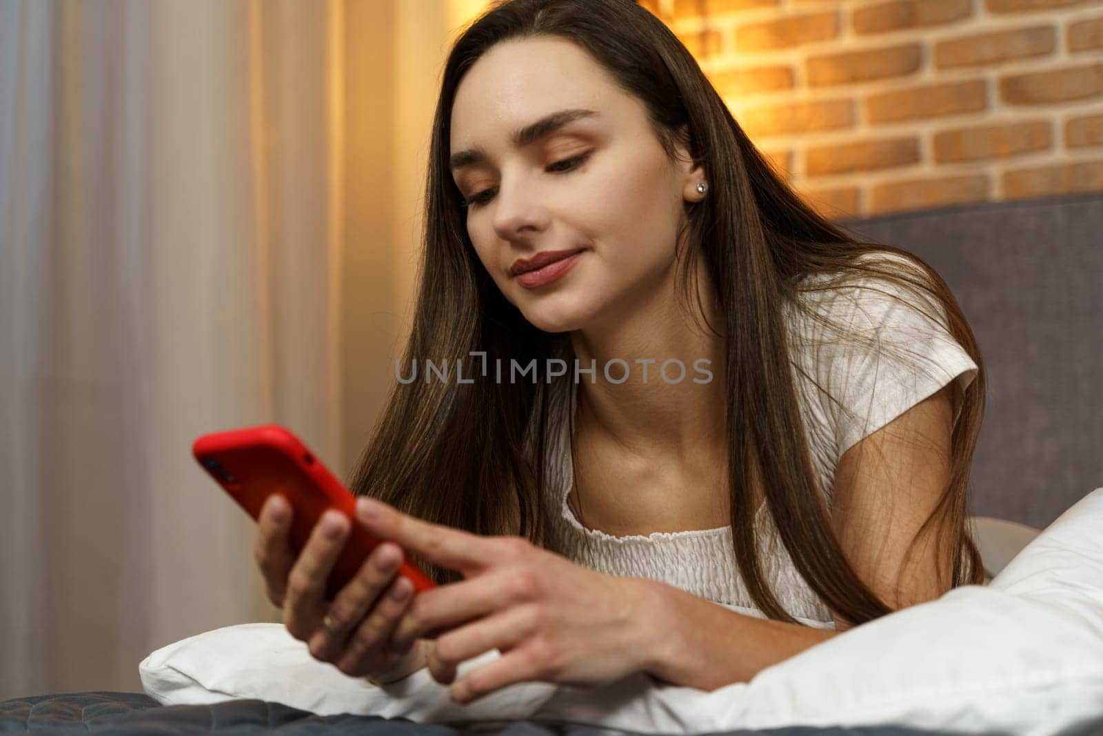 A young woman lies with a smartphone in her hands in the evening on the bed. by Sd28DimoN_1976