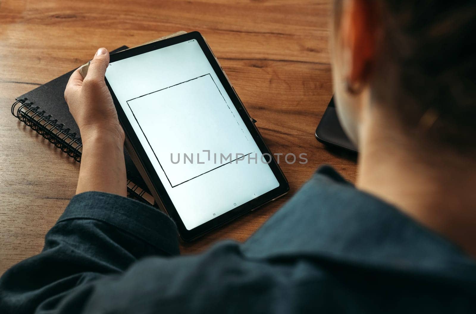 A woman holds a tablet in her hands, on the screen of which there is free space. Mockup. View from above.