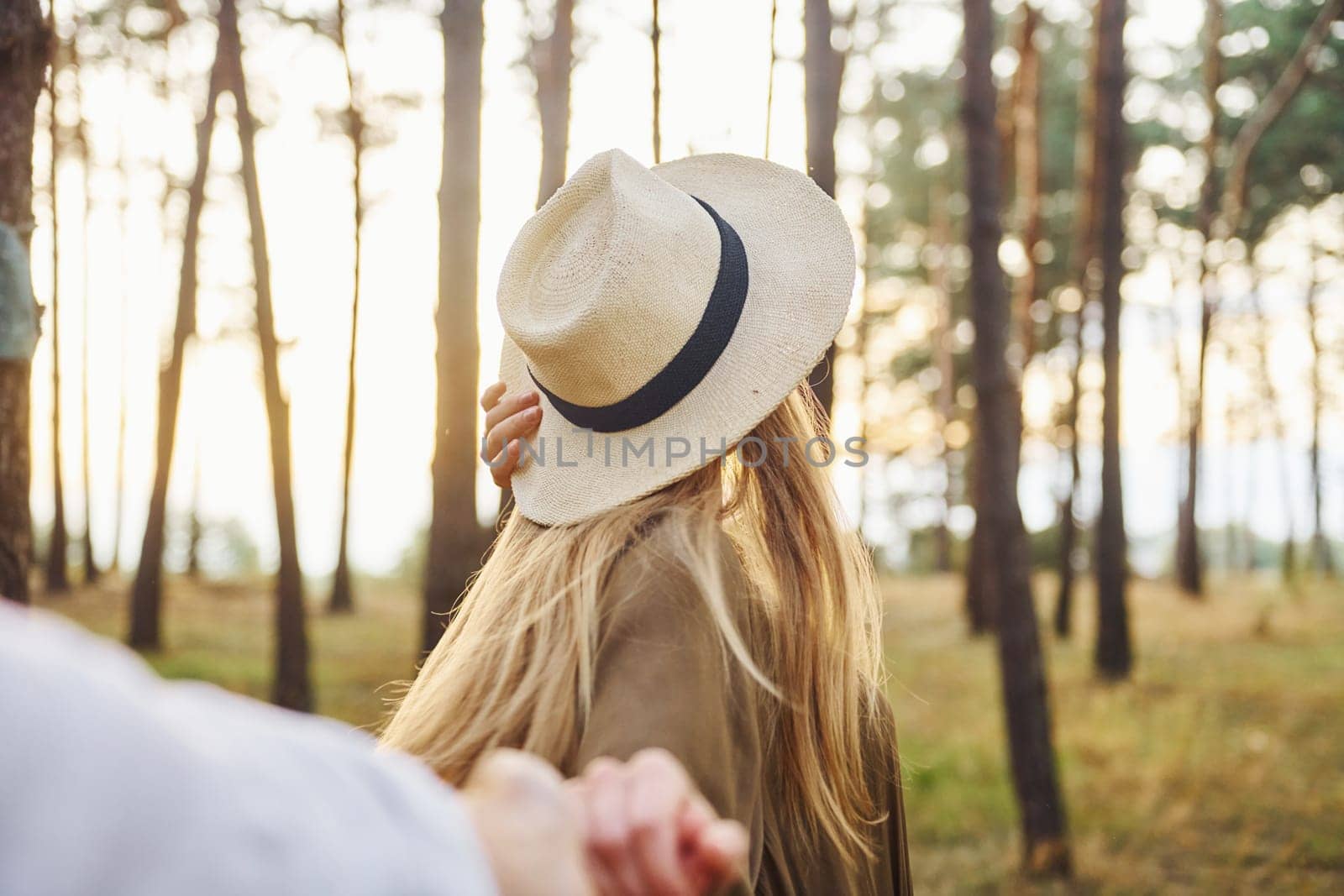 Woman holding man's hand. Happy couple is outdoors in the forest at daytime.