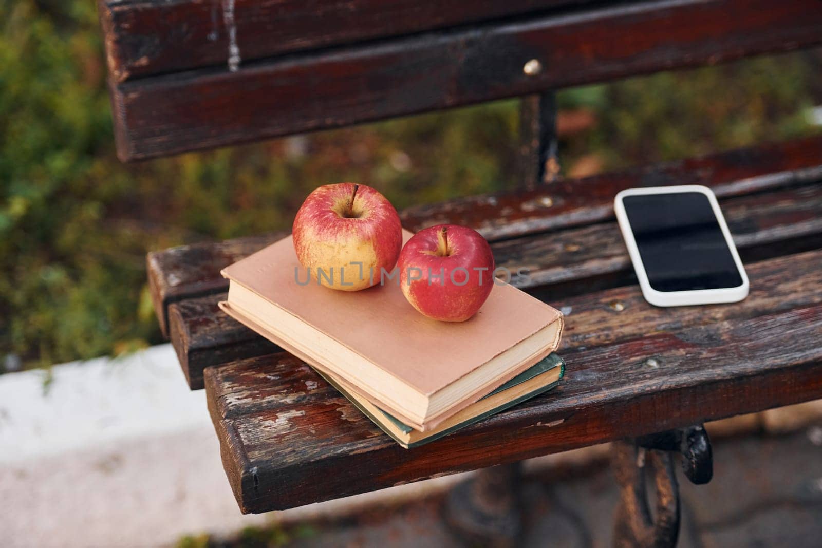 Close up view of couch, and books, apples and smartphone on it.