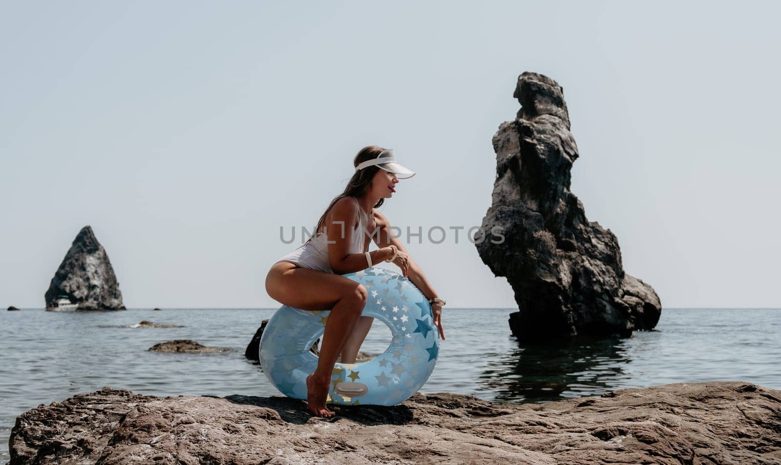 Woman summer sea. Happy woman swimming with inflatable donut on the beach in summer sunny day, surrounded by volcanic mountains. Summer vacation concept