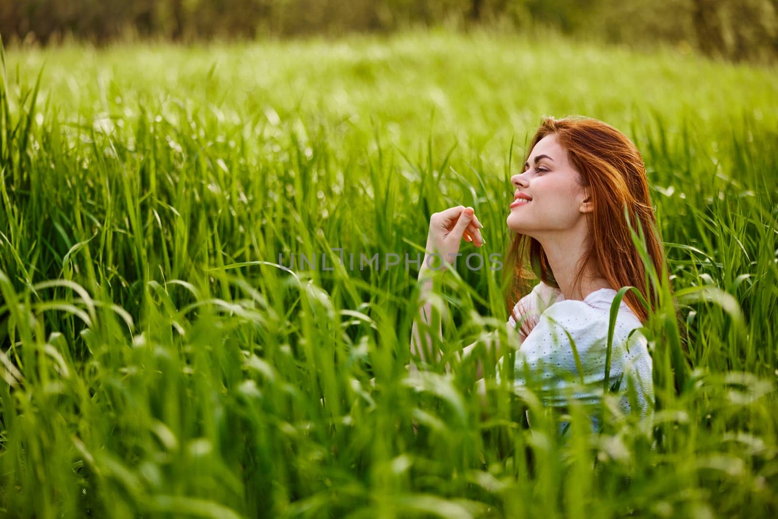 beautiful redhead woman relaxing sitting in tall grass. High quality photo