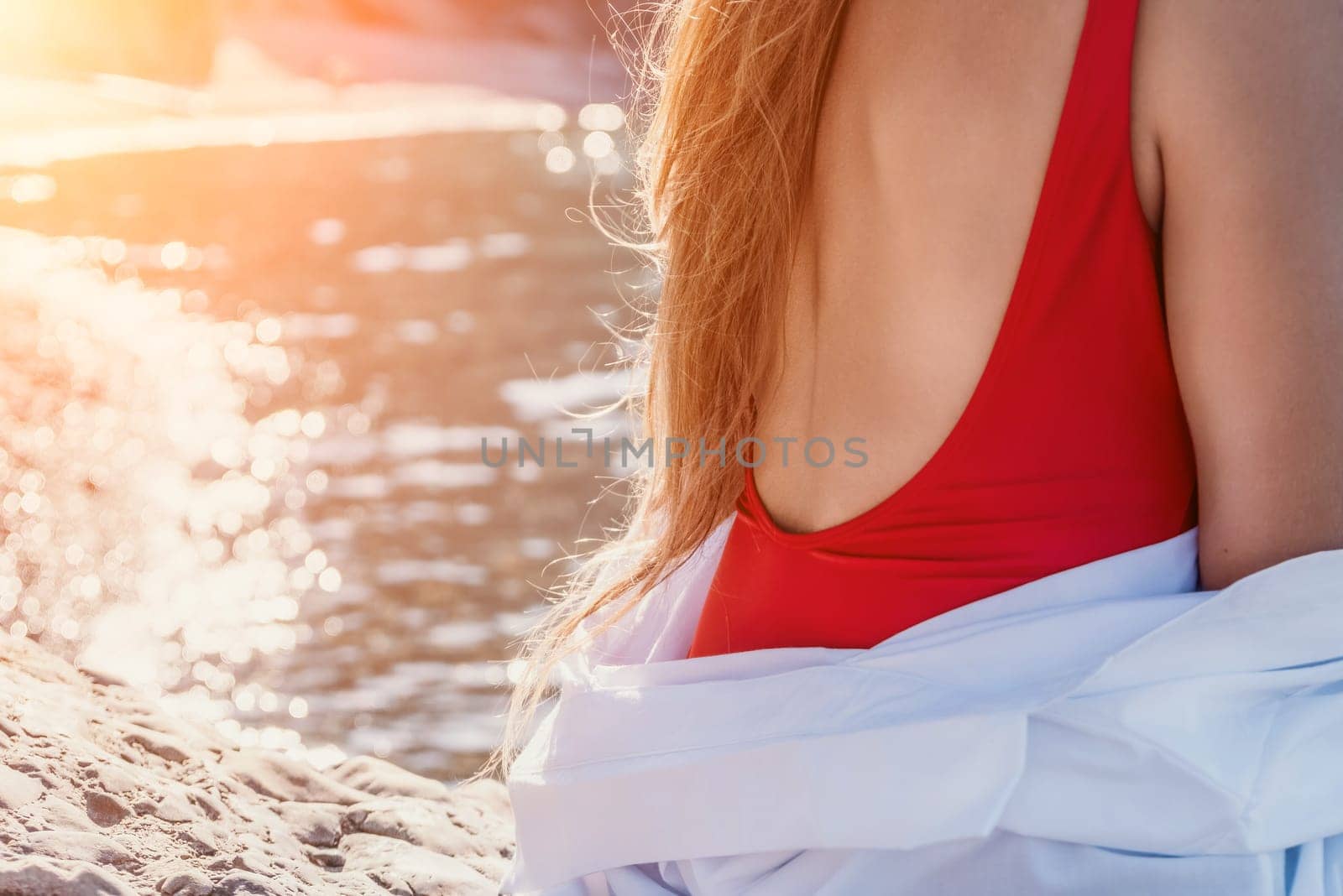 Young woman in red bikini on Beach. Girl lying on pebble beach and enjoying sun. Happy lady in bathing suit chilling and sunbathing by turquoise sea ocean on hot summer day. Close up. Back view by panophotograph