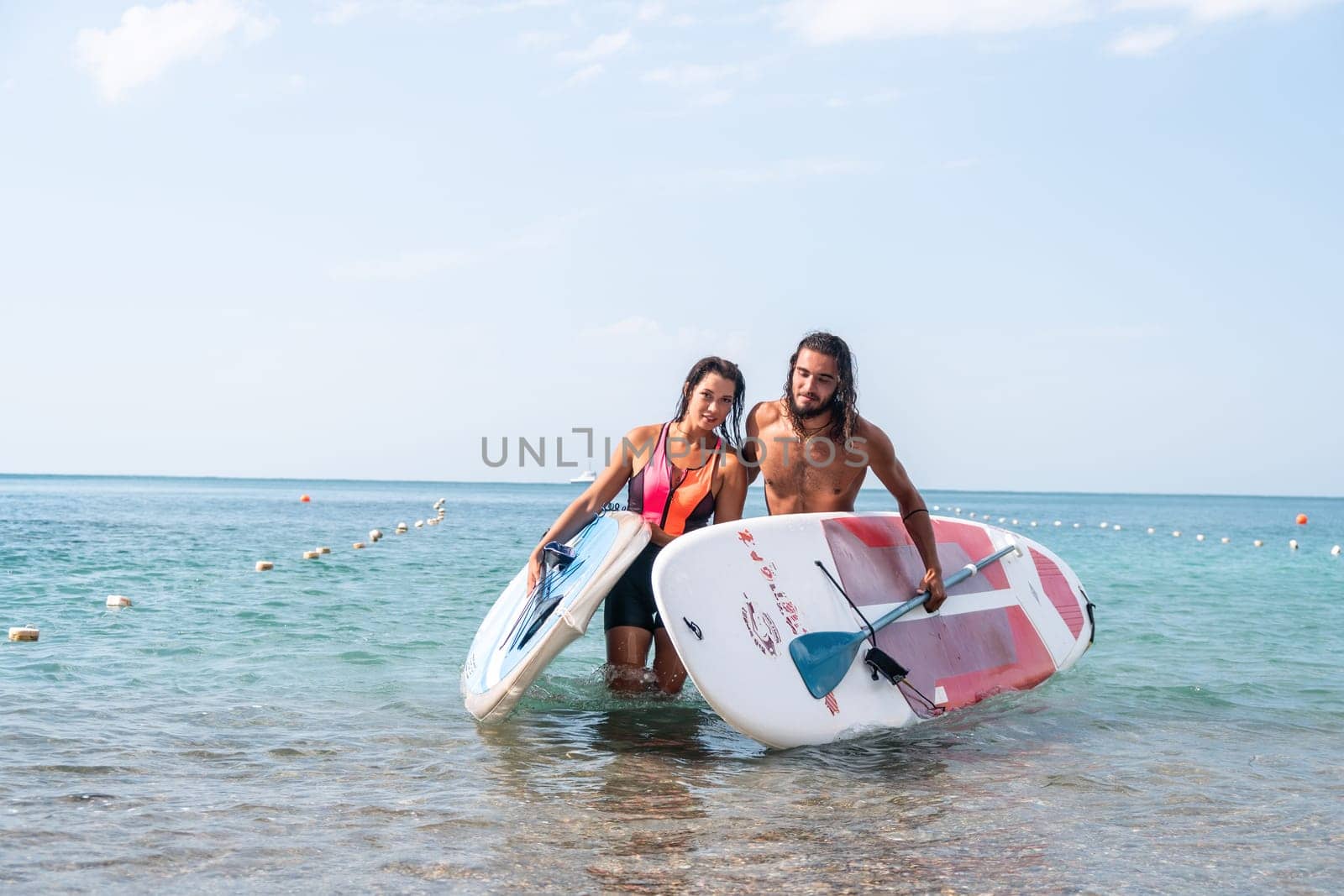 Woman man sea sup. Close up portrait of beautiful young caucasian woman with black hair and freckles looking at camera and smiling. Cute woman portrait in a pink bikini posing on sup board in the sea by panophotograph