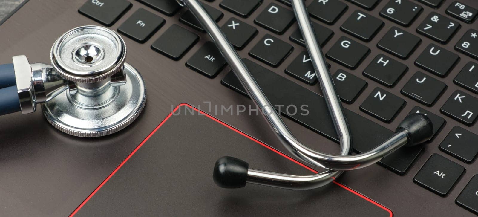 Silver stethoscope on a modern laptop keyboard. Medical concept