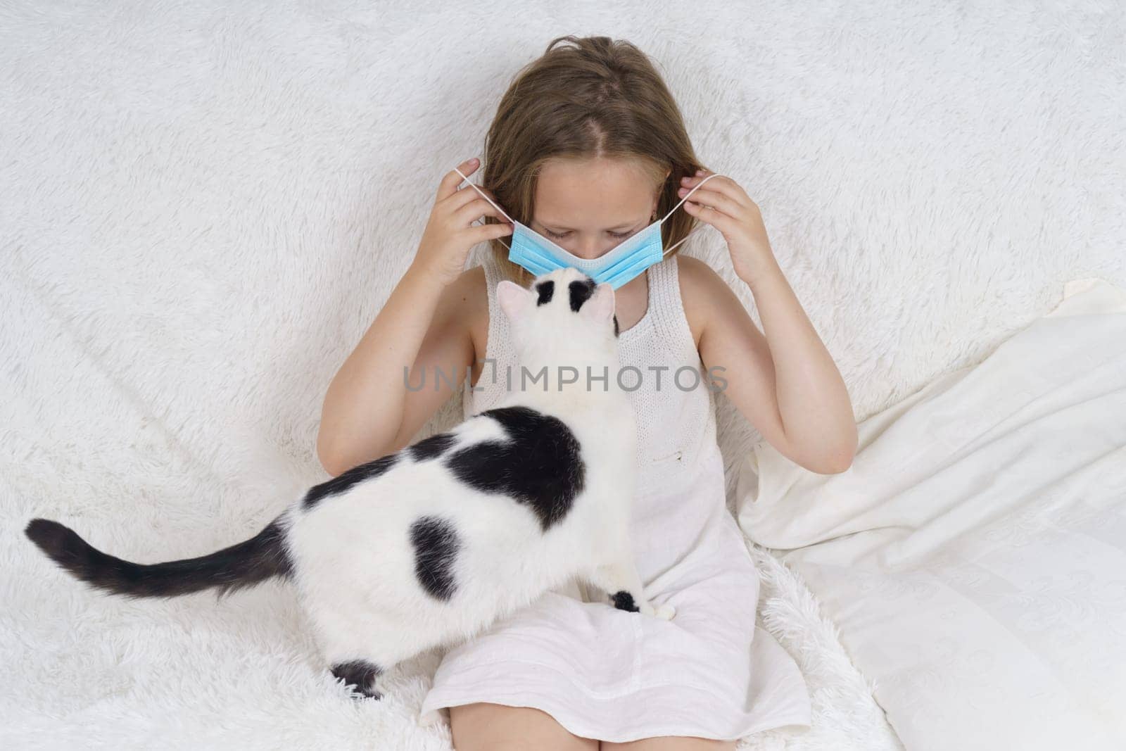 Sick teenage girl in a protective mask, next to her is a cat. Medical concept.
