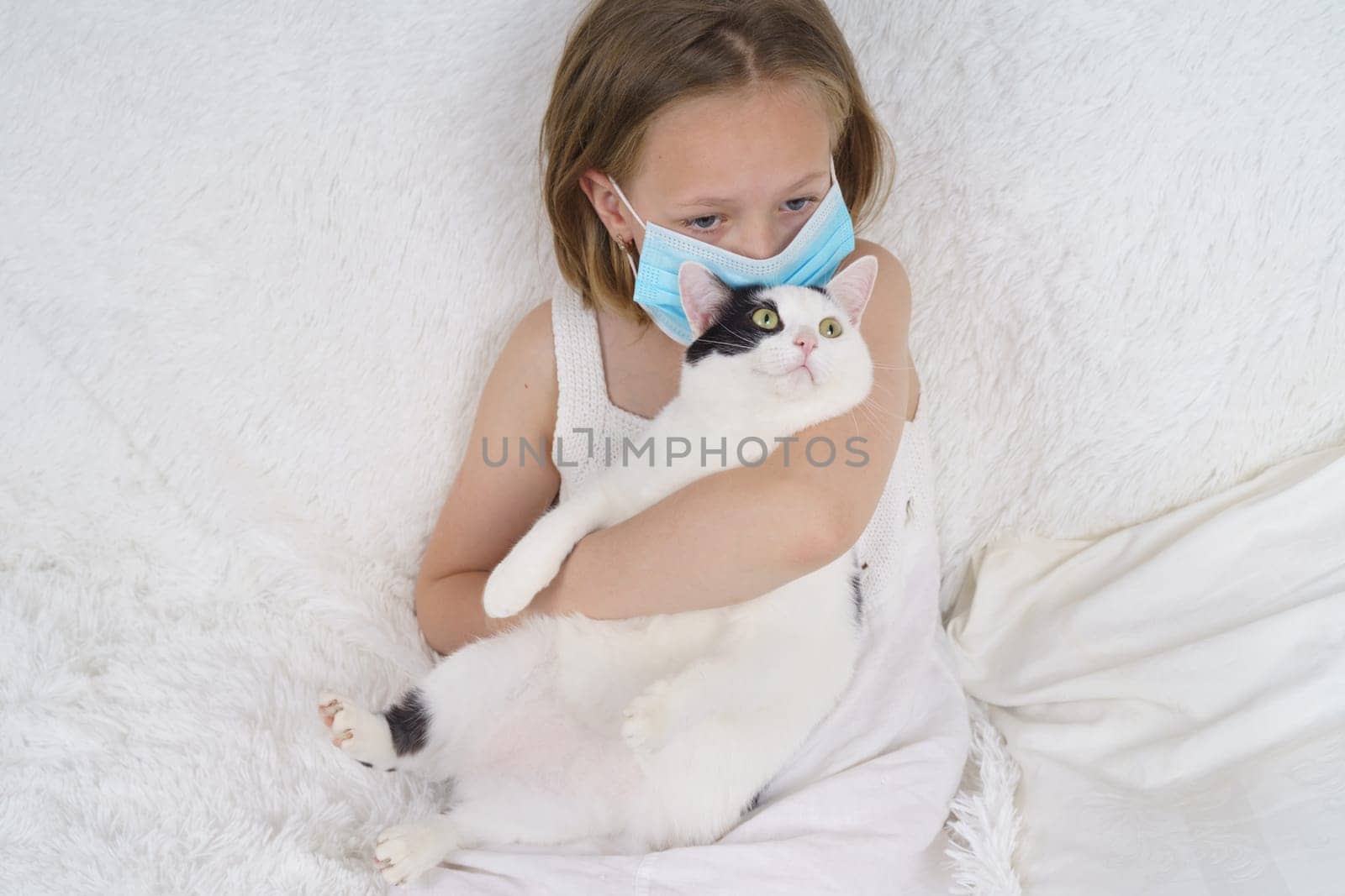 Sick teenage girl in a protective mask hugs a cat. Medical concept.