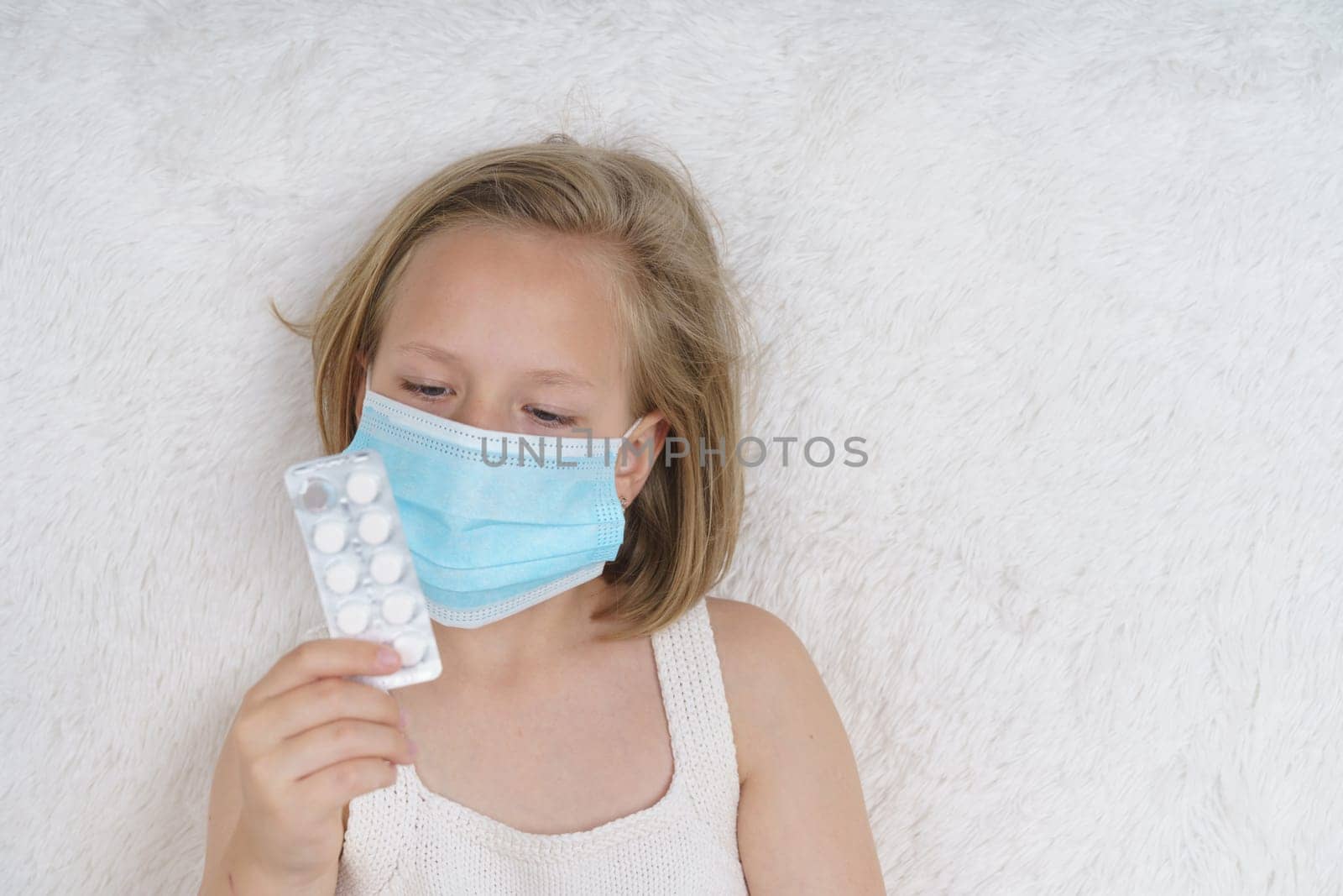 Sick teenage girl is looking through the packaging with pills. Medical concept.