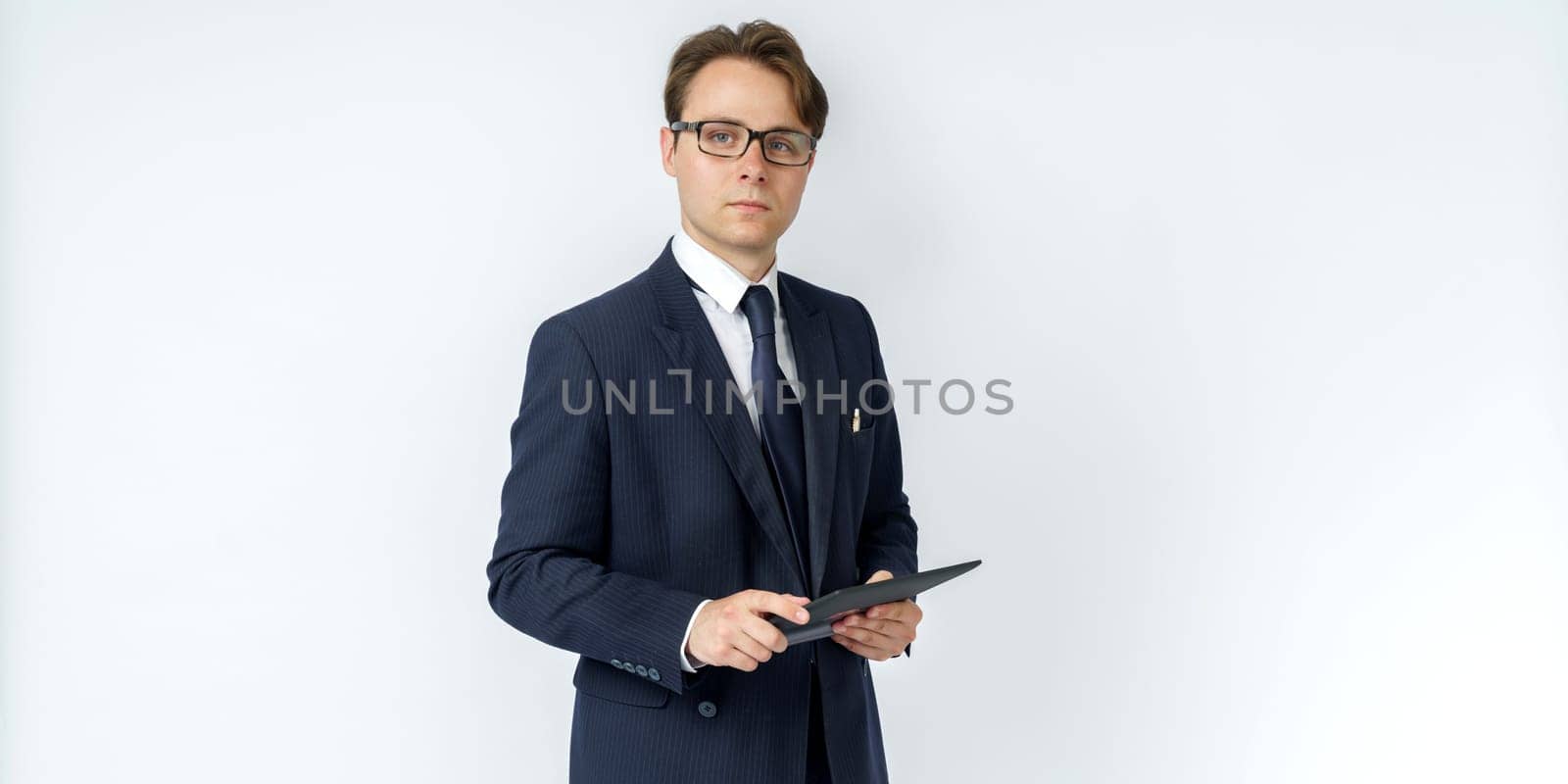 Portrait of a businessman in a blue suit holding an electronic tablet on a white background. No face visible. Business and finance concept