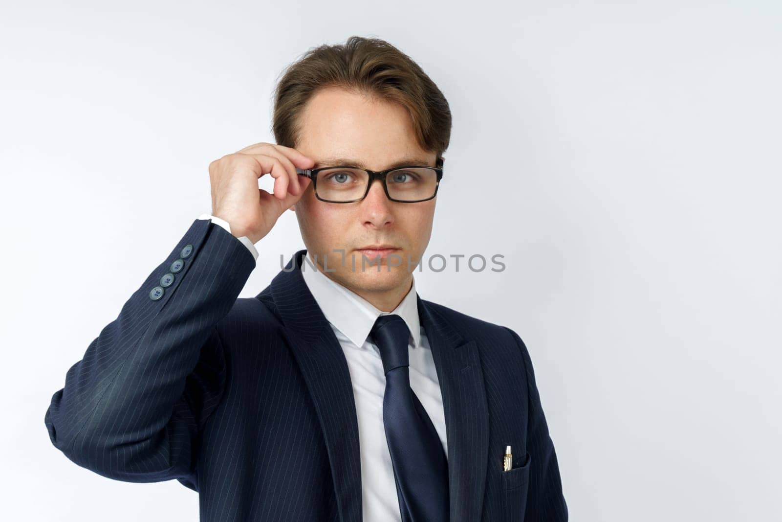Portrait of a businessman in a blue suit, who adjusts his glasses. White background. Business and finance concept
