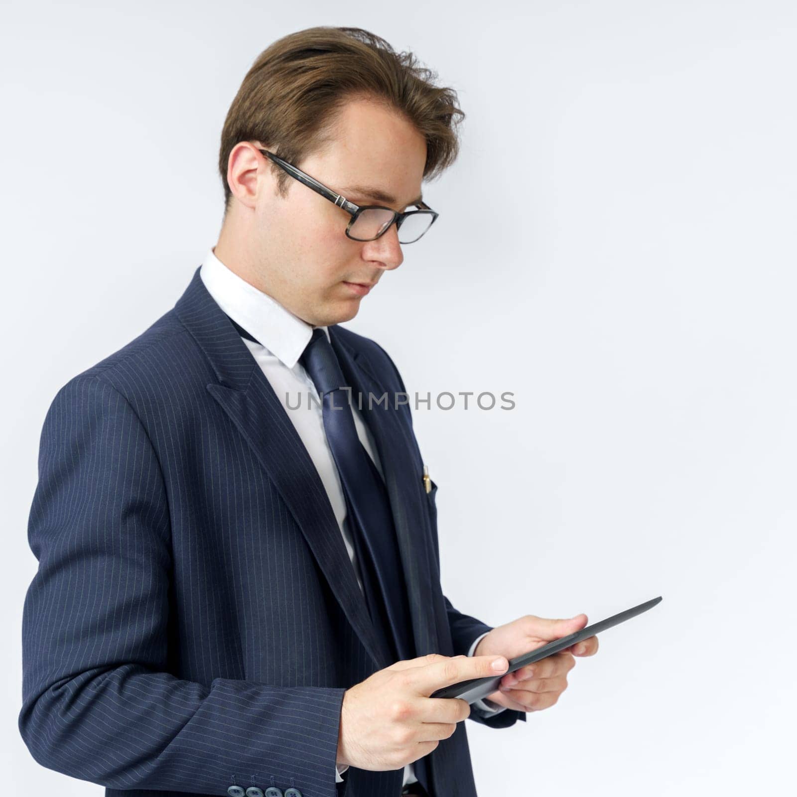 Portrait of a businessman in a blue suit holding an electronic tablet in his hands. White background. Business and finance concept