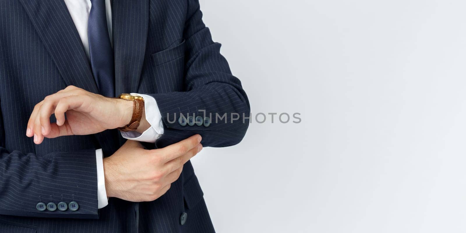 Portrait of a businessman in a blue suit straightening his suit. No face visible. White background. Business and finance concept