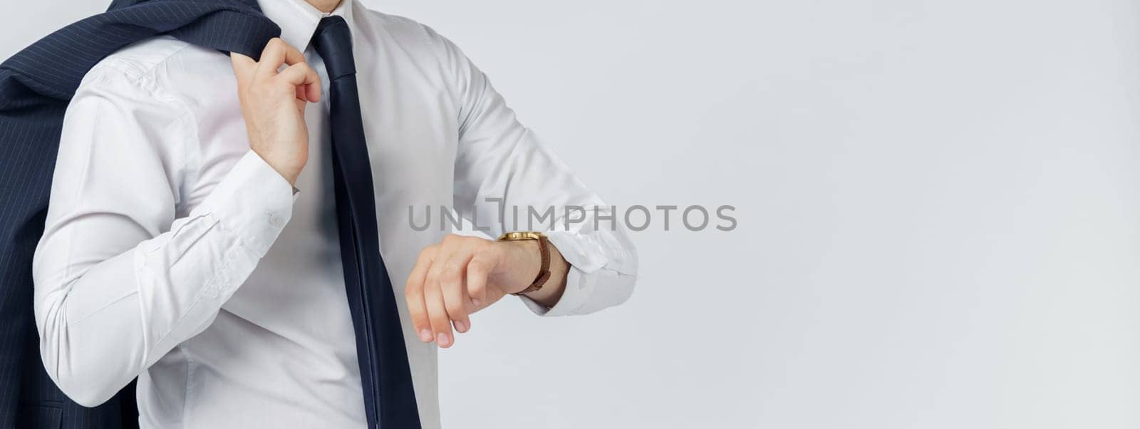 Portrait of a businessman in a blue suit who looks at his watch. No face visible. White background. Business and finance concept