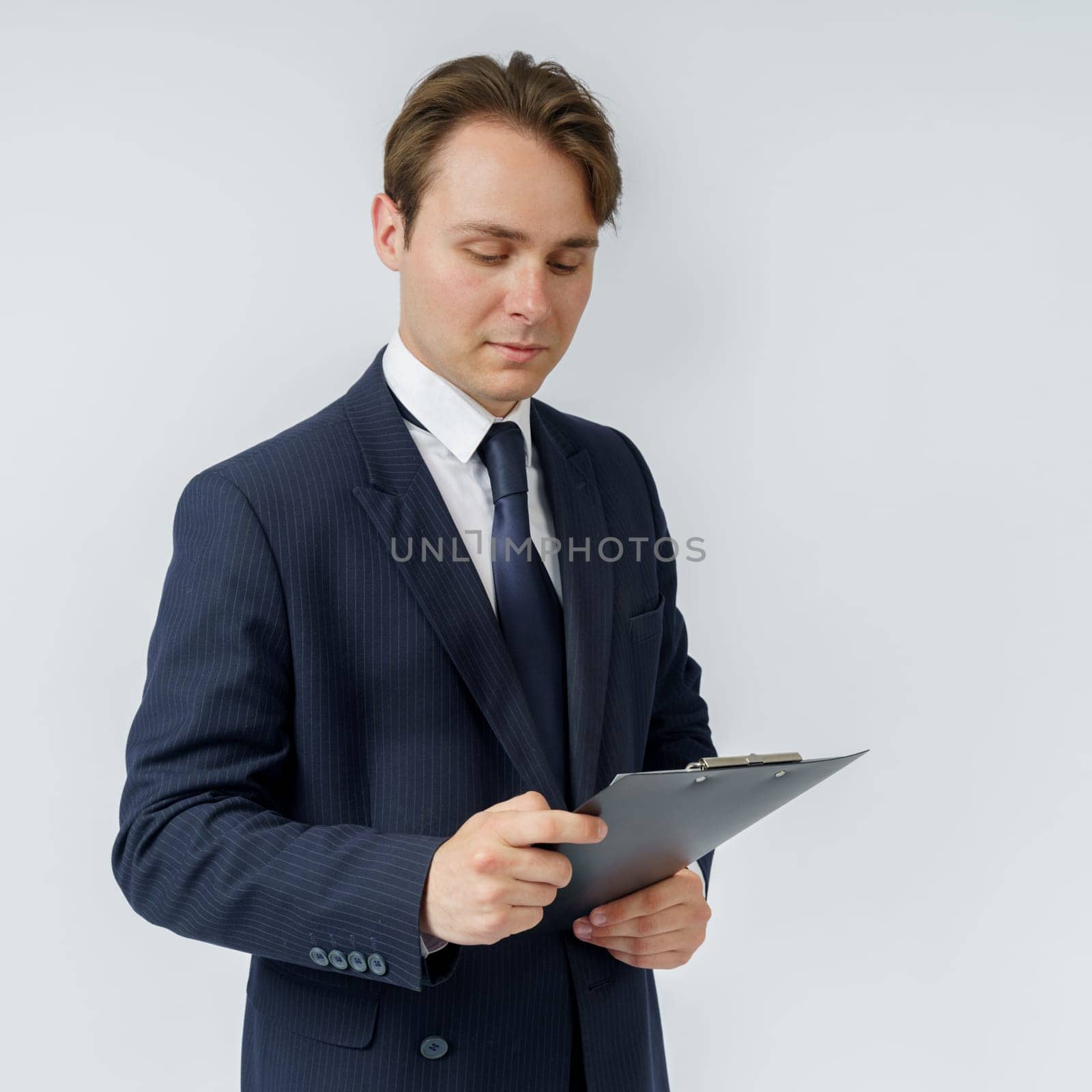 A businessman in a blue suit holds a folder in his hands and reads reports on a white background. Business and finance concept