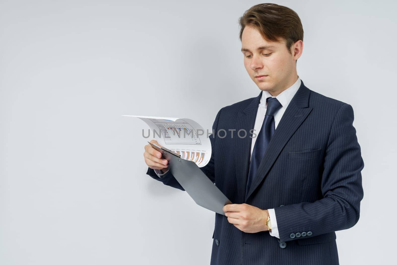 A businessman in a blue suit holds a folder in his hands and reads reports on a white background. Business and finance concept