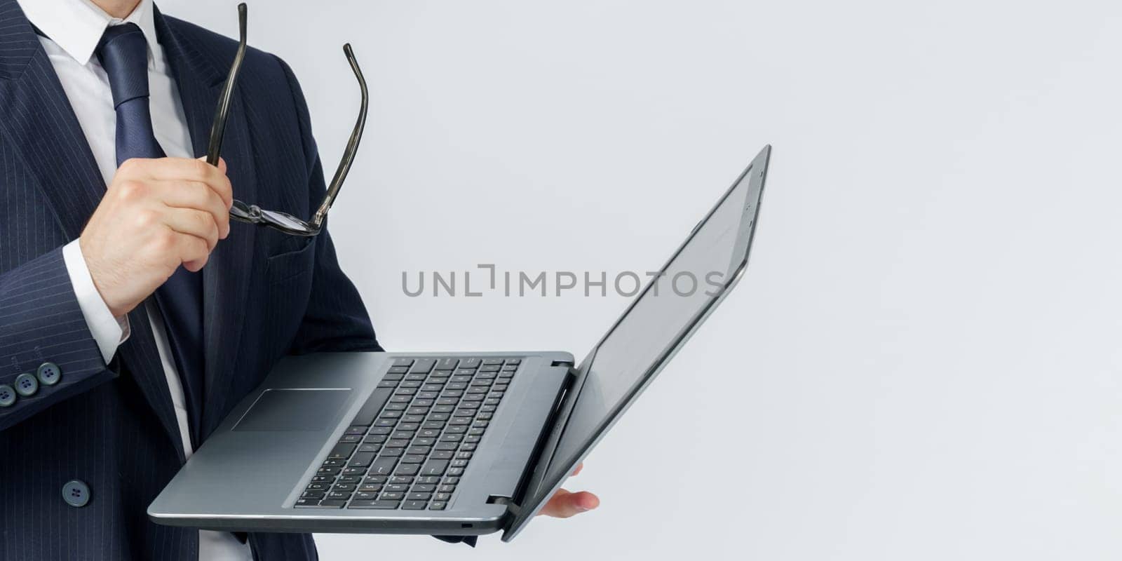 Portrait of a businessman who is holding a laptop and glasses. No face visible. White background. Business and finance concept