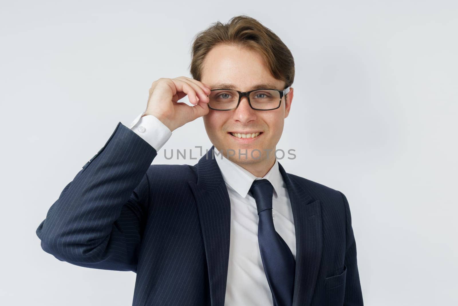 Portrait of a businessman in a blue suit, who adjusts his glasses. White background. Business and finance concept