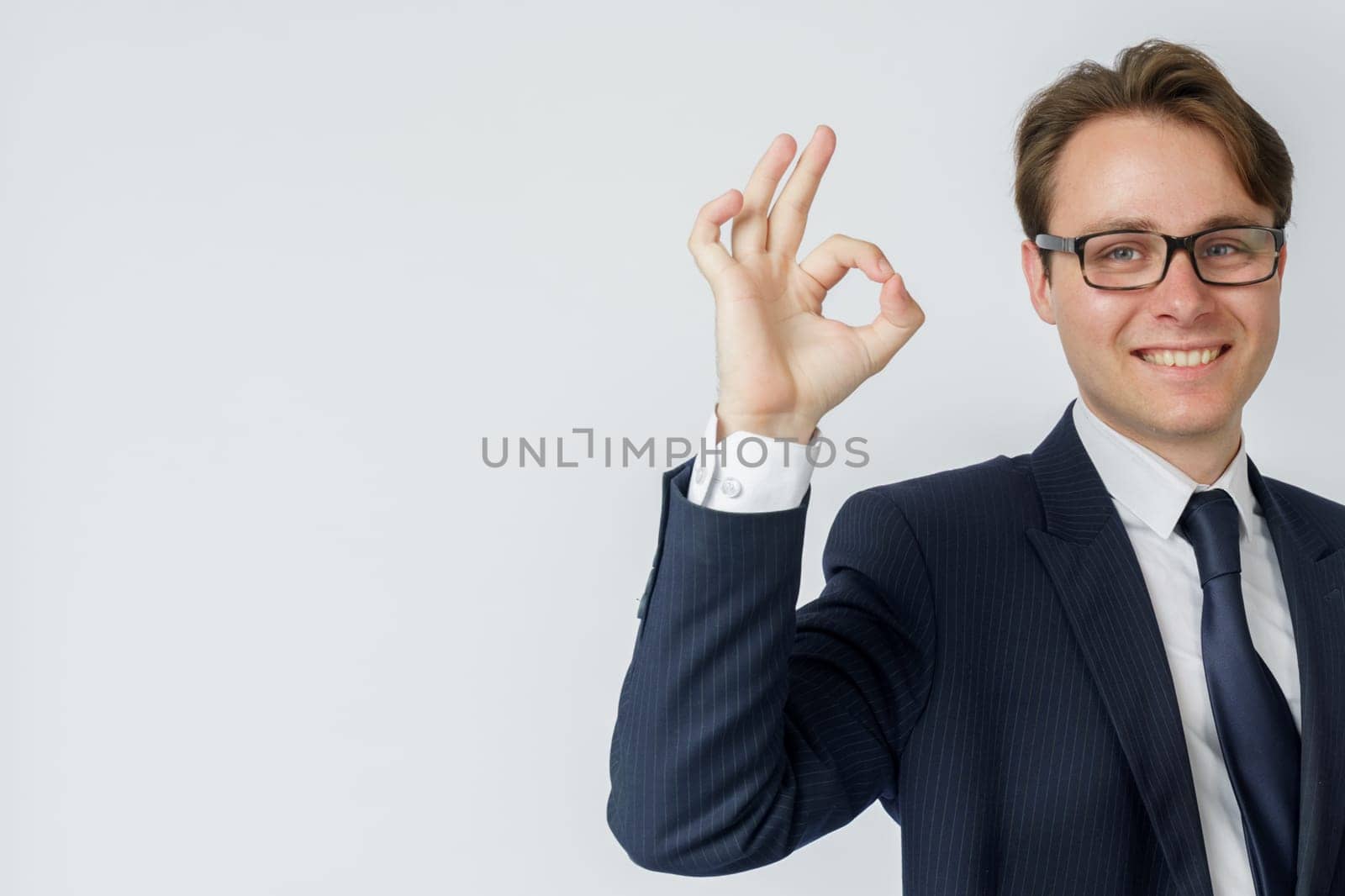 Businessman shows hand gesture OK. White background. Business and finance concept