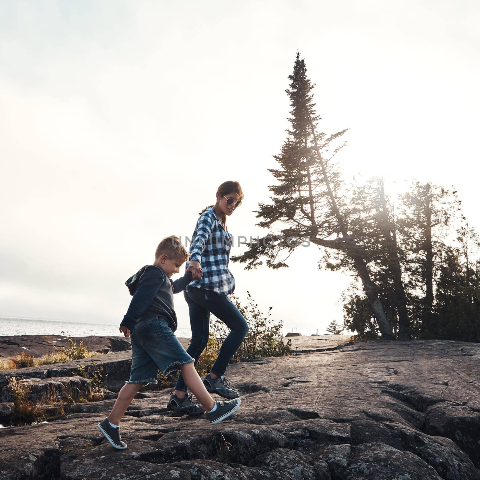 Taking a nice and easy stroll. a cheerful mother and son holding hands while walking outside in nature during the day. by YuriArcurs