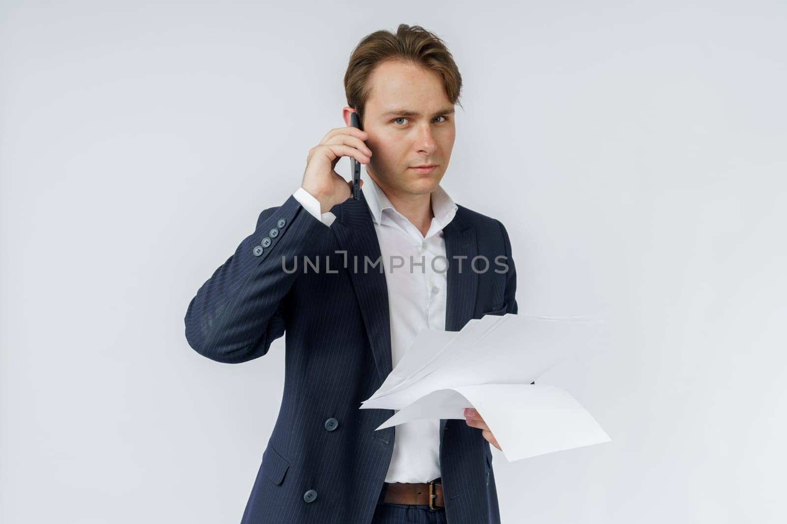 Portrait of a businessman who is talking on the phone and reading documents. White background. Business and finance concept by Sd28DimoN_1976