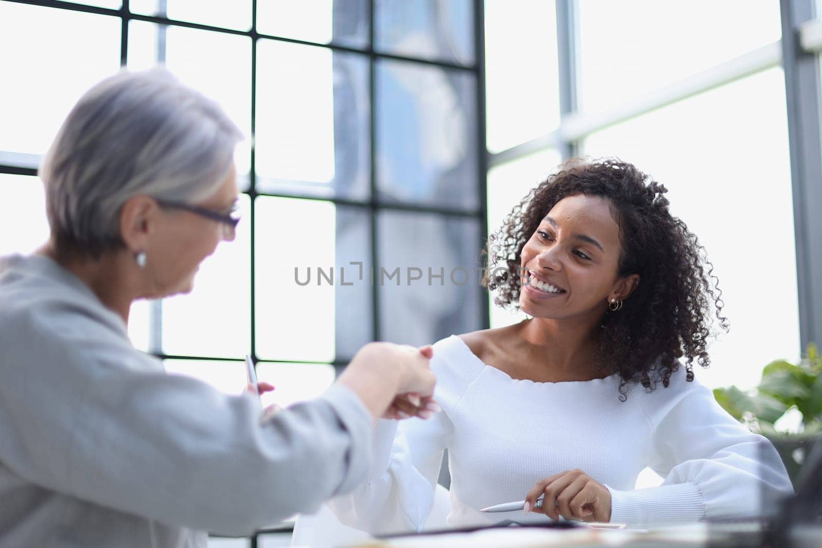 Business women smile and shaking hands at a table in the boardroom in the office,