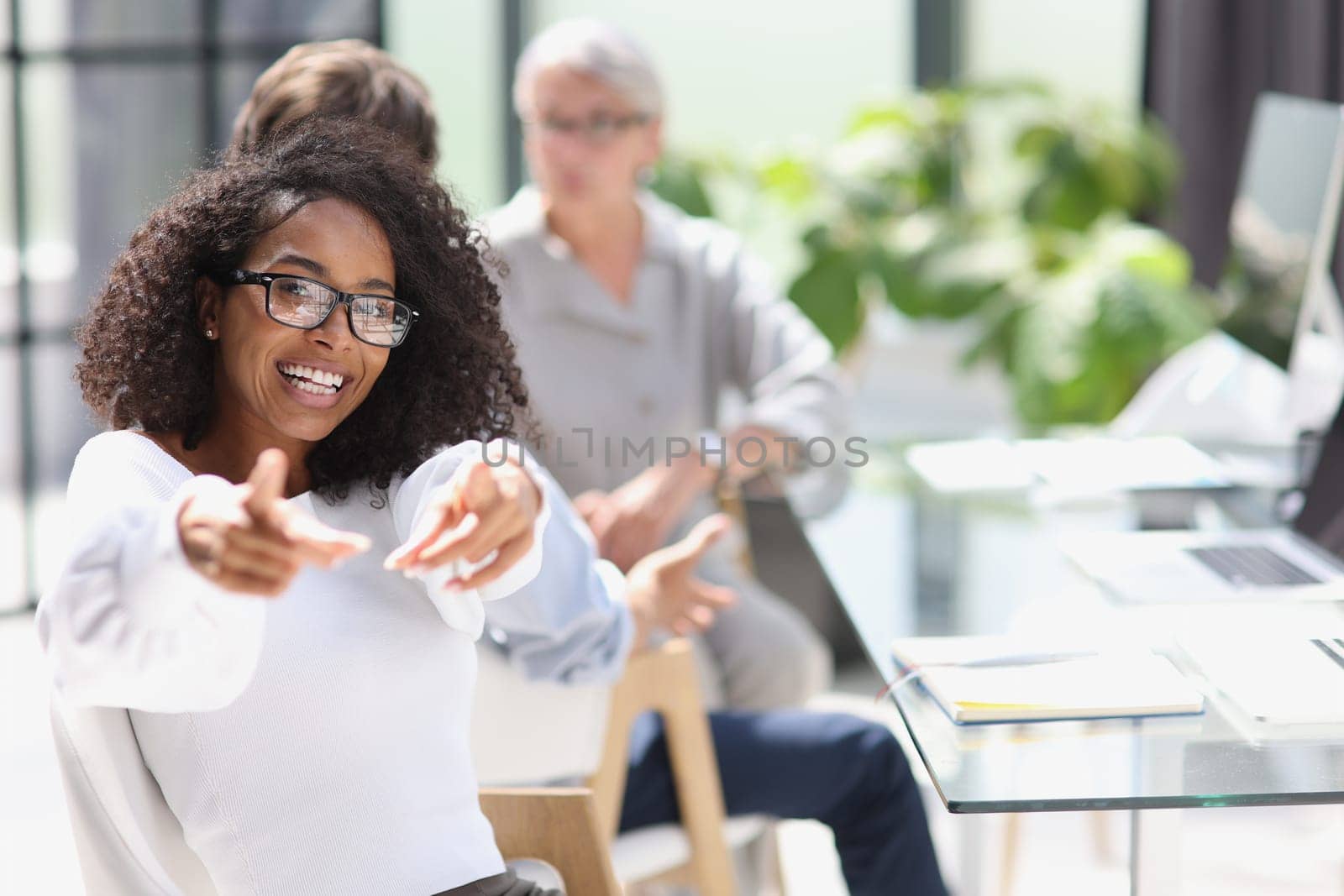 Young business woman sits at the table and rejoices in success.