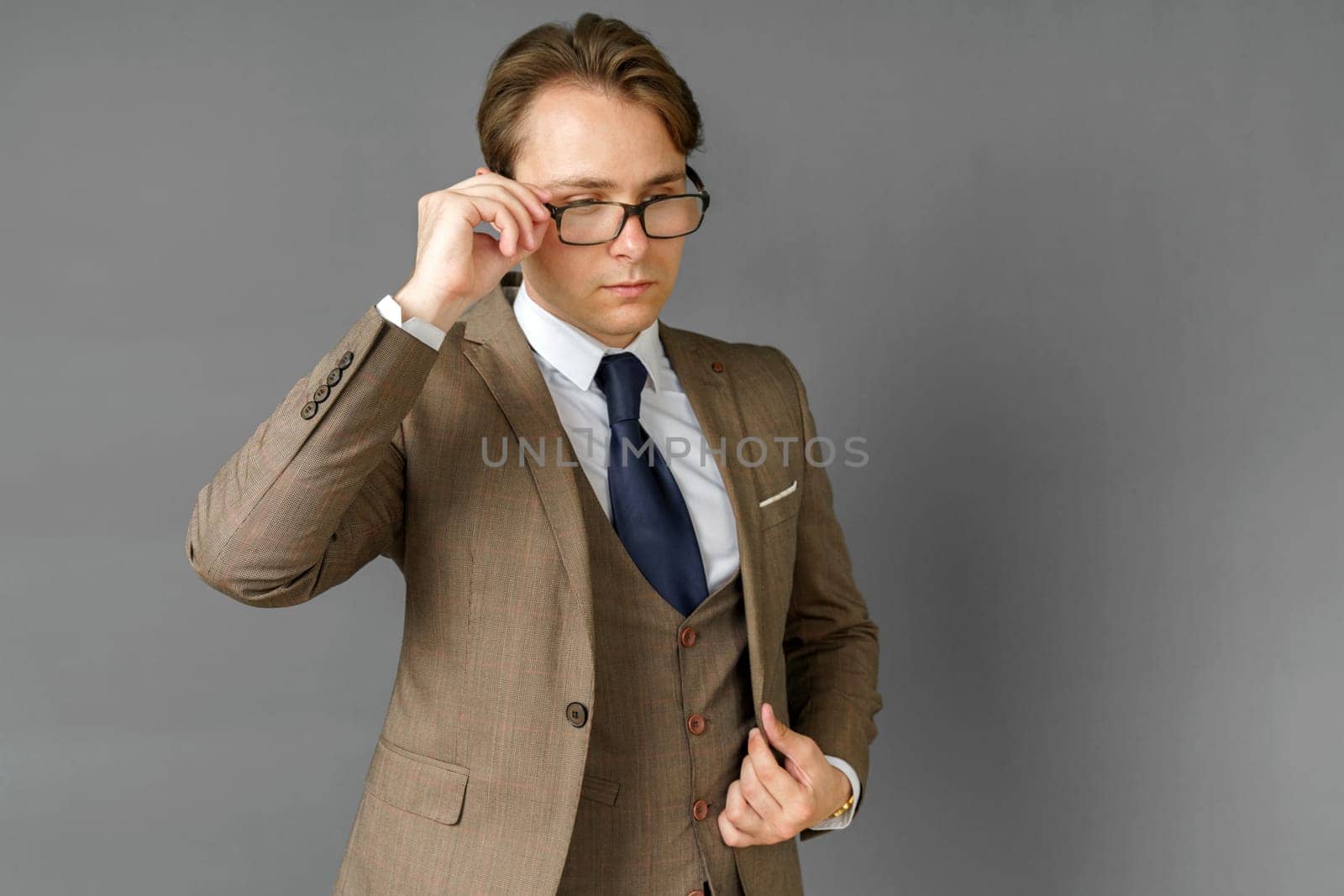 Portrait of a businessman in a suit, who adjusts his glasses. Gray background. Business and finance concept