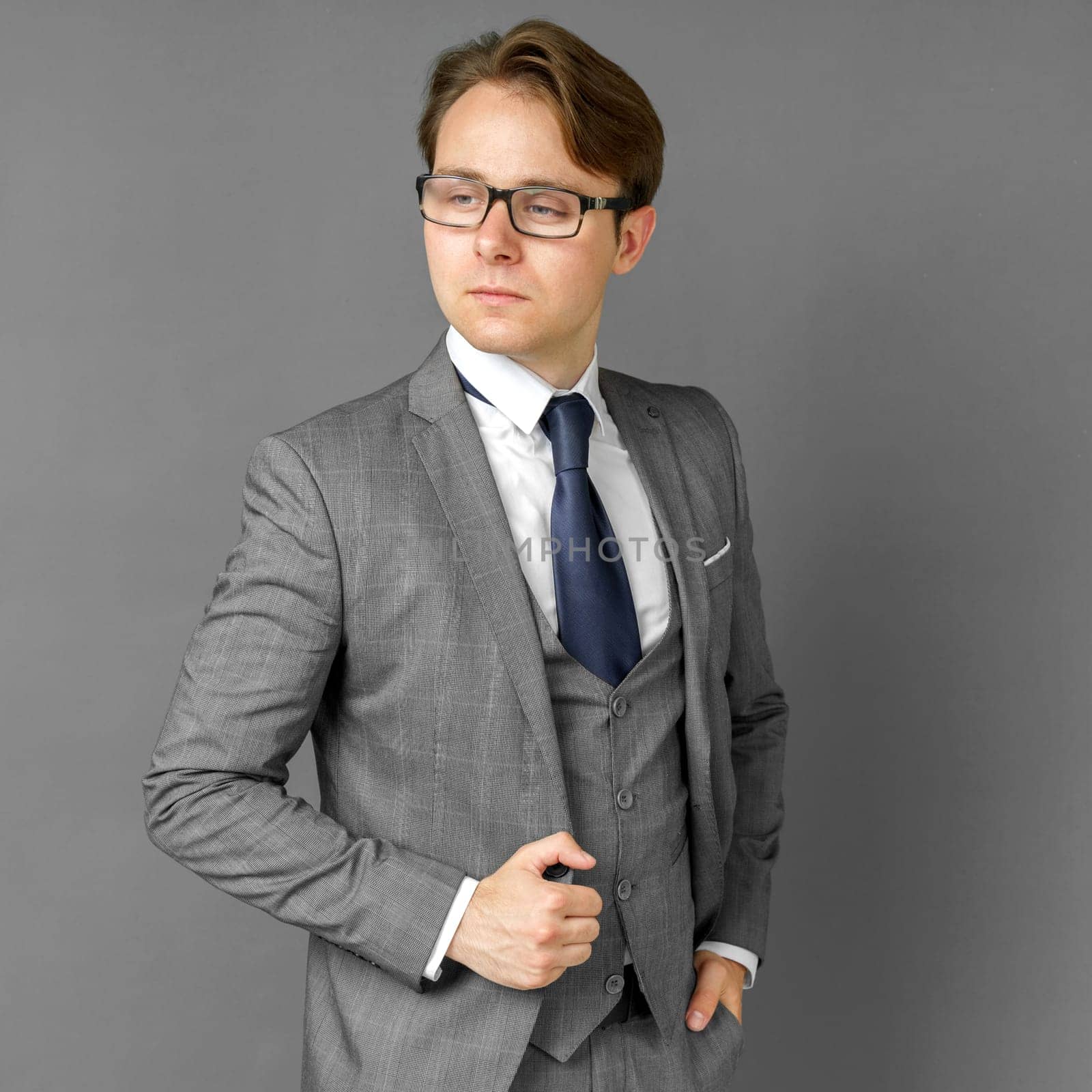 Portrait of a businessman in a suit who is looking to the side. Gray background concept of business and finance