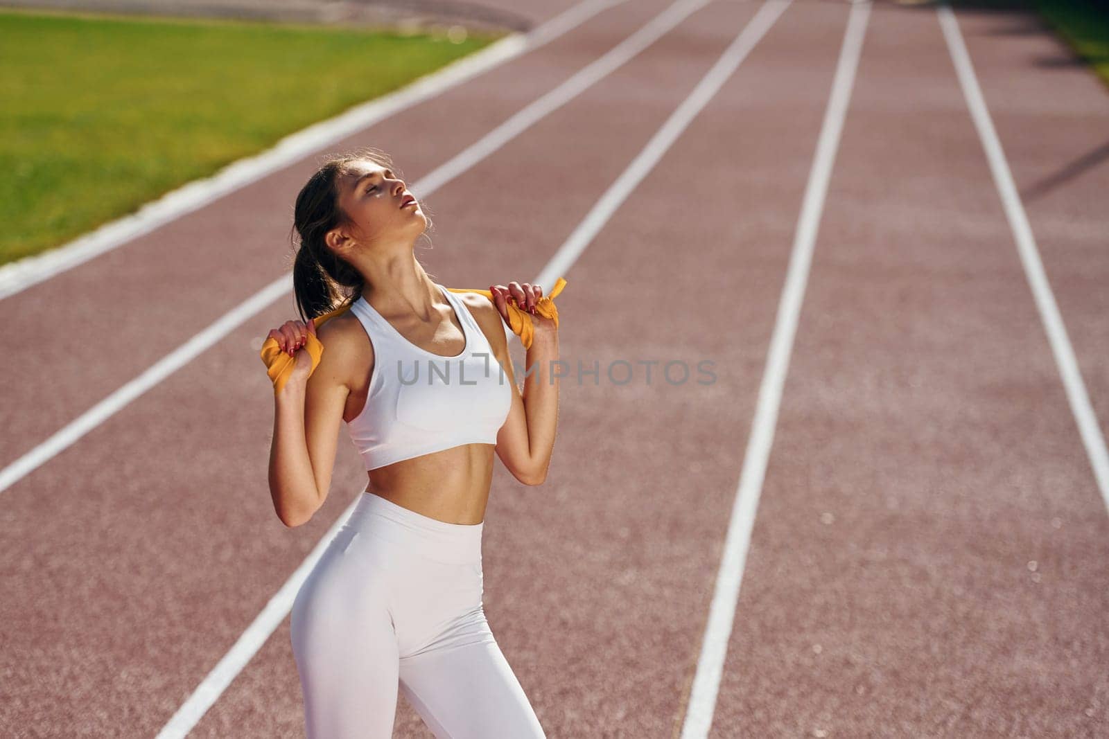 On the running track. Young woman in sportive clothes is exercising outdoors.